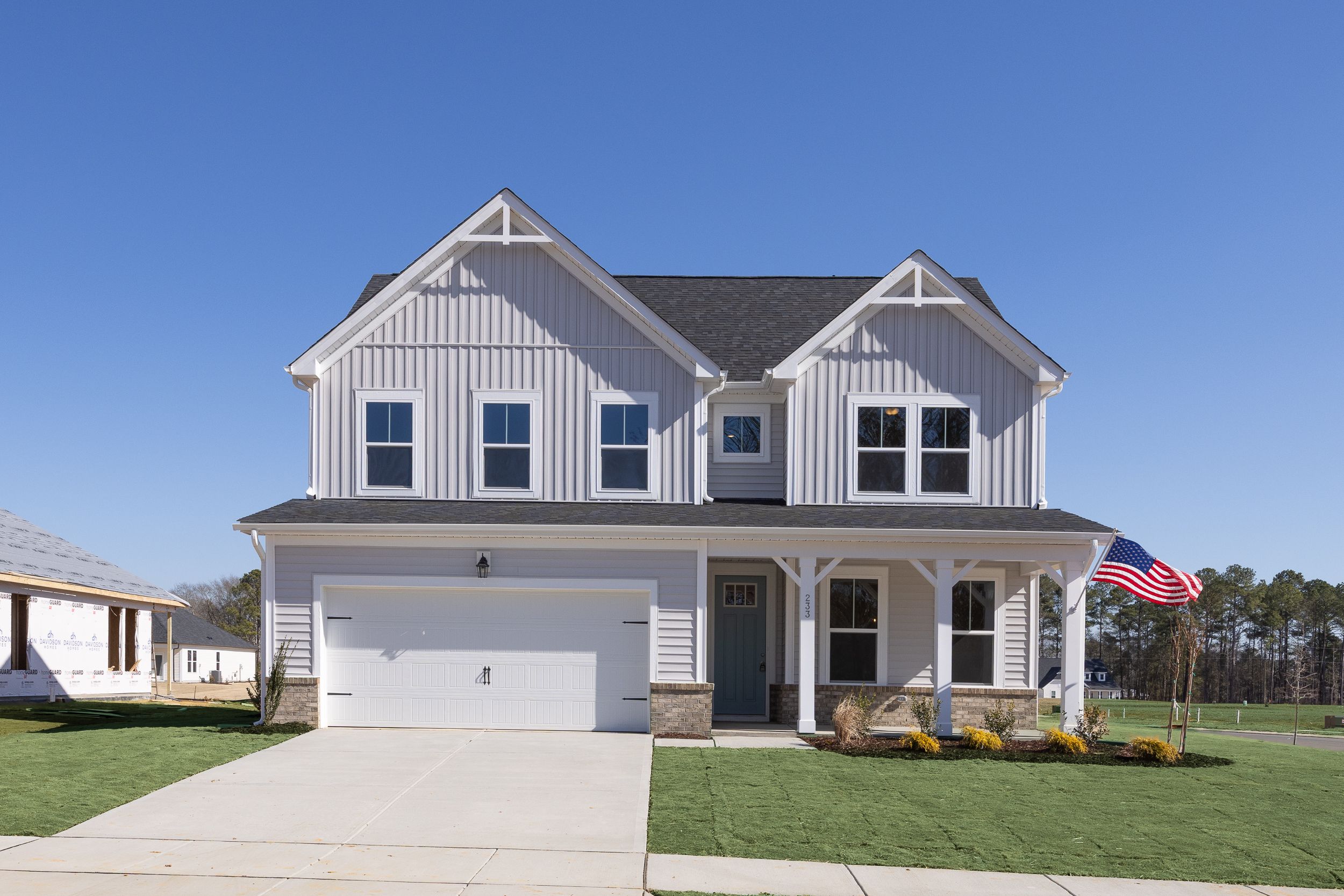 Two-story Davidson Homes exterior at Woodland Crossing in Zebulon, NC with board and batten siding and front porch.