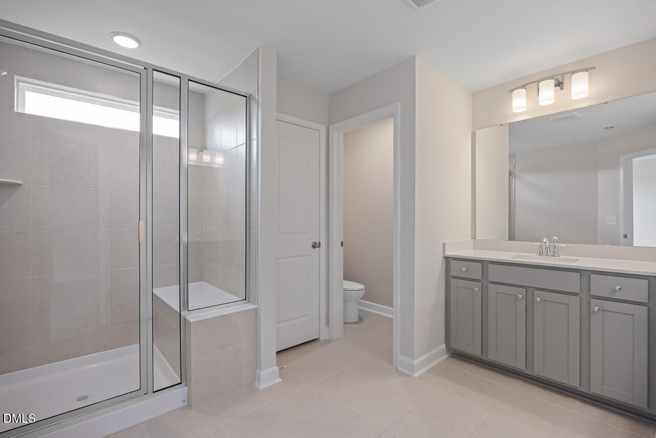 Modern bathroom with walk-in glass shower and grey vanity in The Graham floor plan at Springvale, Fuquay-Varina, NC.