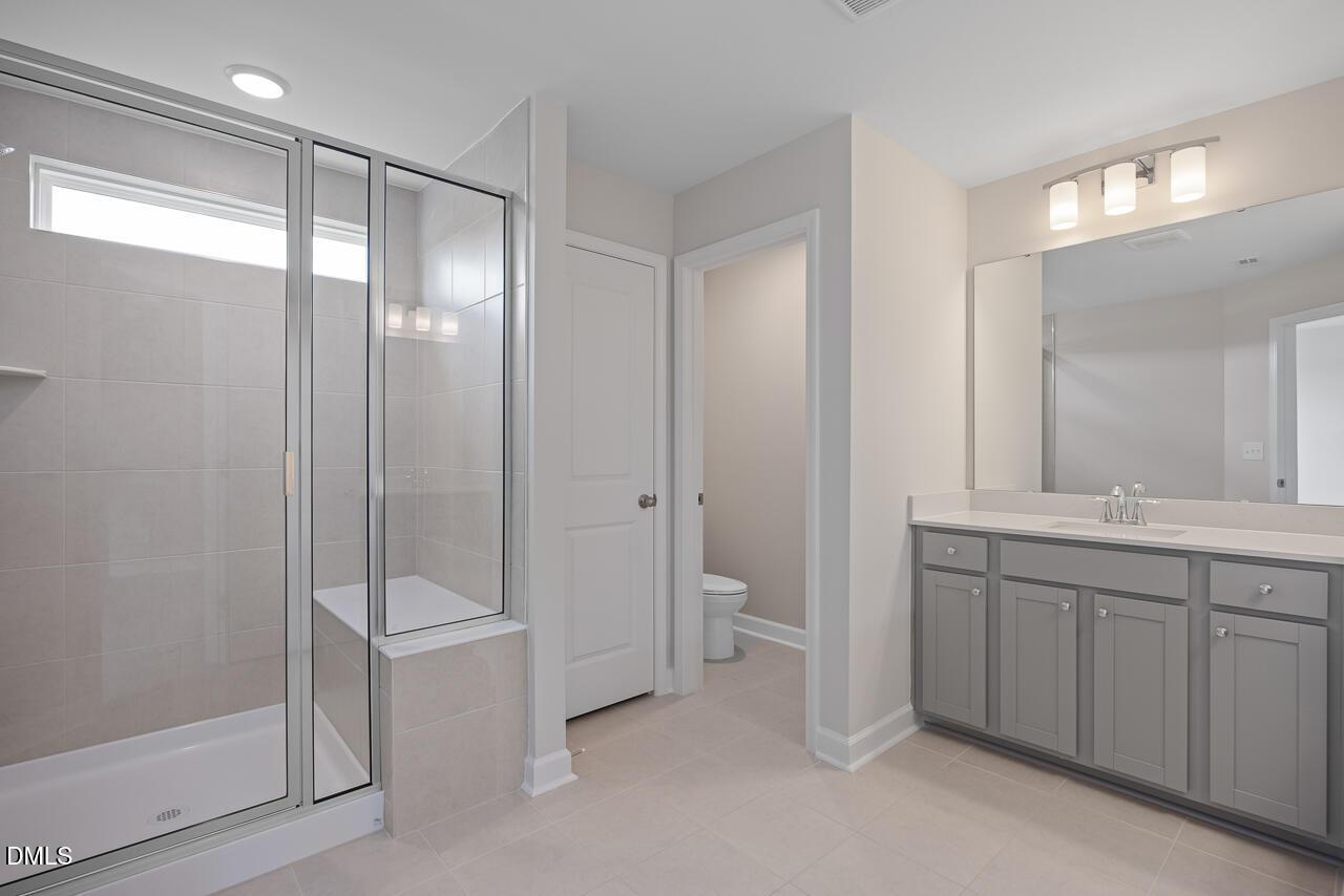 Modern bathroom with walk-in glass shower and grey vanity in The Graham floor plan at Springvale, Fuquay-Varina, NC.