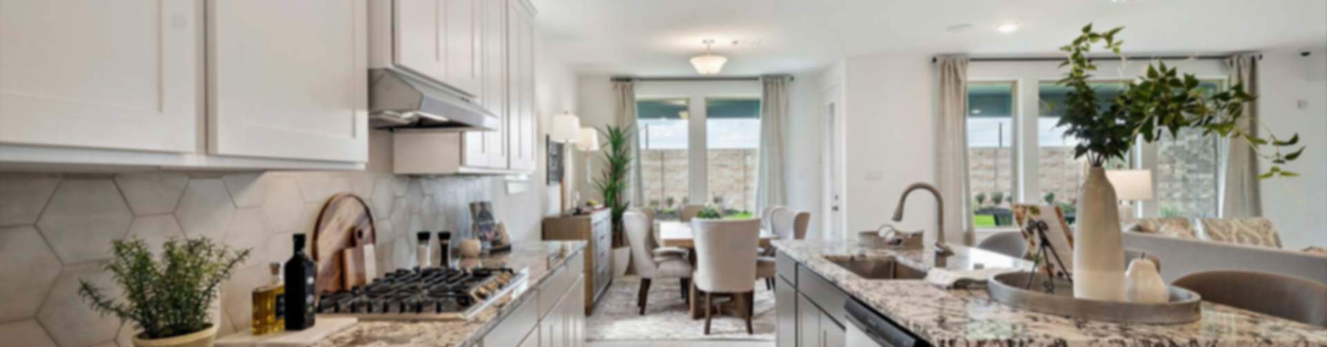 Modern open-concept kitchen with white cabinets, granite island, and adjacent dining area in Rosharon home