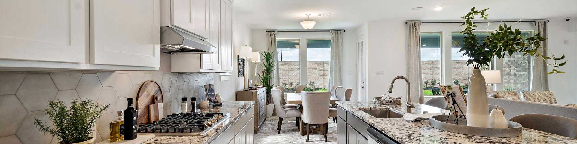 Modern open-concept kitchen with white cabinets, granite island, and adjacent dining area in Rosharon home