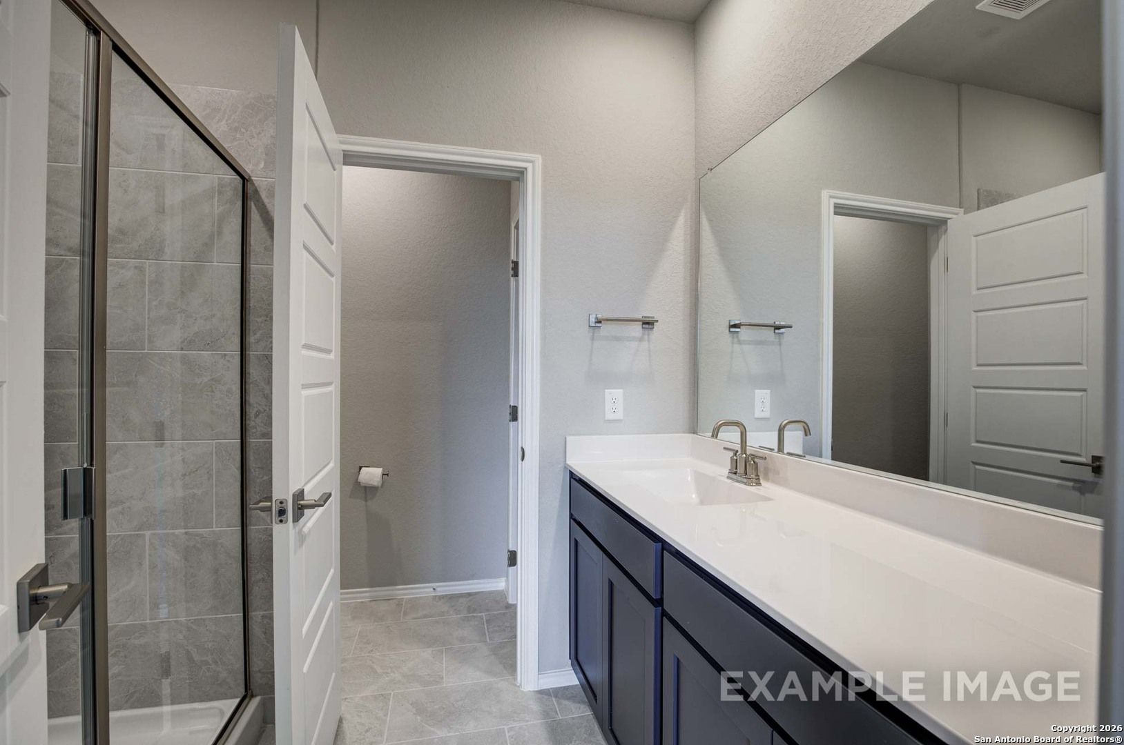 Modern master bathroom with glass shower, navy double vanity, and large mirror in Davidson Homes The Frio B, Agave, San Antonio