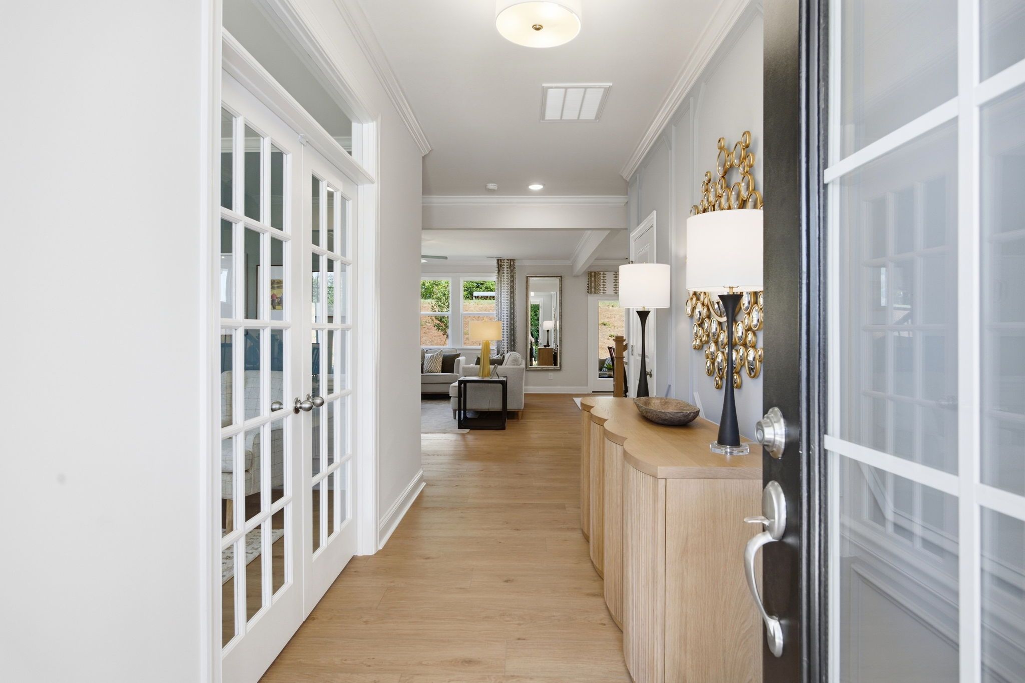 Spacious entry hallway with oak hardwood floors, white French doors, and console table at Enclave at Belmont in Belmont NC