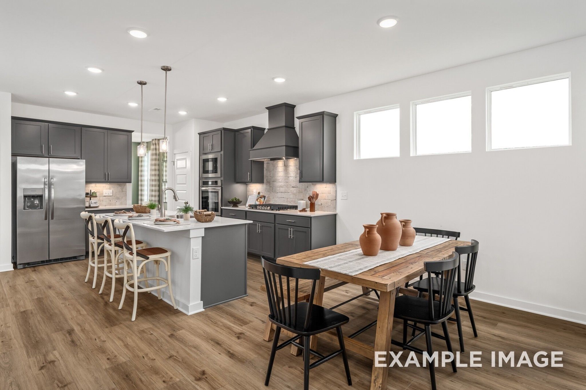 Modern kitchen with dark gray cabinets and dining area in The Ash A floor plan at Woods Crossing, Gallatin, Tennessee.