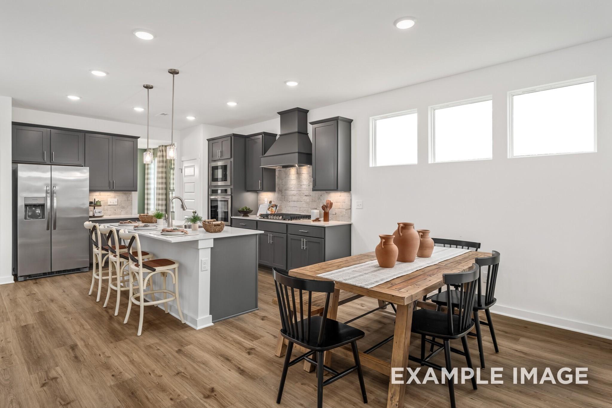 Modern kitchen with dark gray cabinets and dining area in The Ash A floor plan at Woods Crossing, Gallatin, Tennessee.