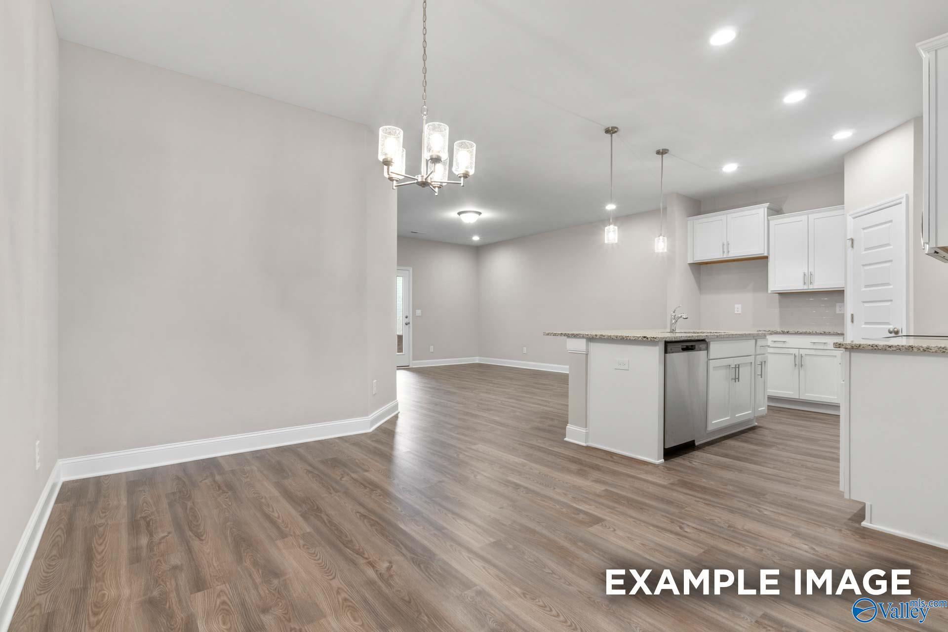 Open-concept kitchen and dining area with white cabinets, granite island, stainless appliances, hardwood floors in Davidson Homes The Camilla C, Hartselle, AL