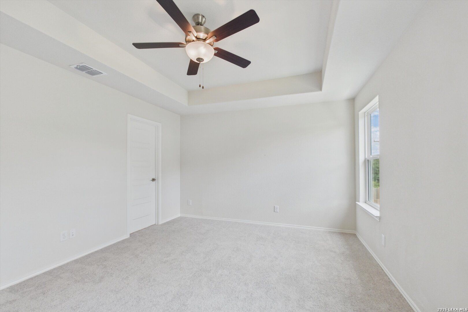 Bright bedroom with tray ceiling and ceiling fan in The Charlotte B floor plan at Meadows at Oak Creek, San Antonio.