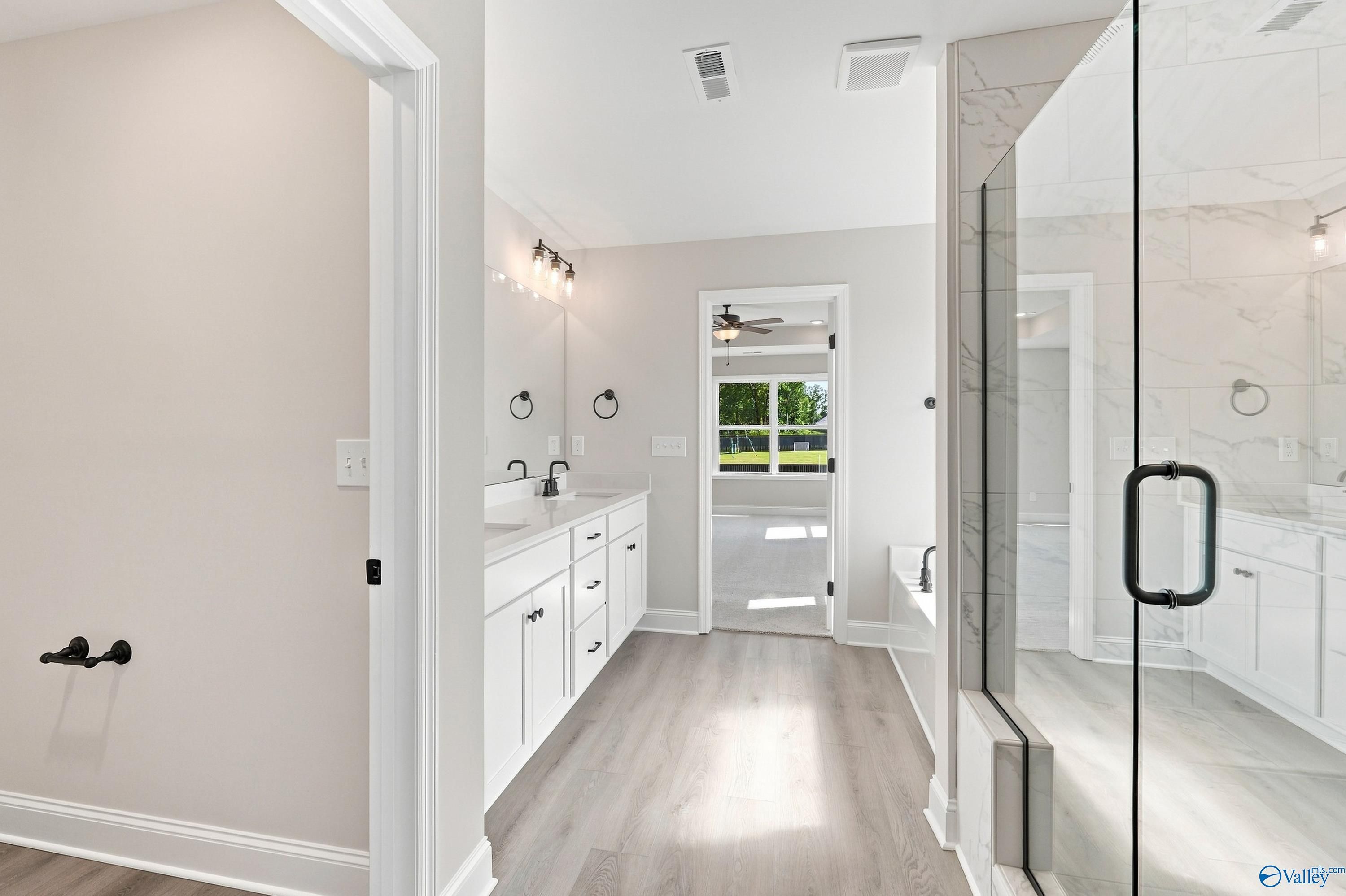 Modern primary bathroom with dual vanity, glass walk-in shower, and soaking tub in Davidson Homes Chelsea B, New Market, AL