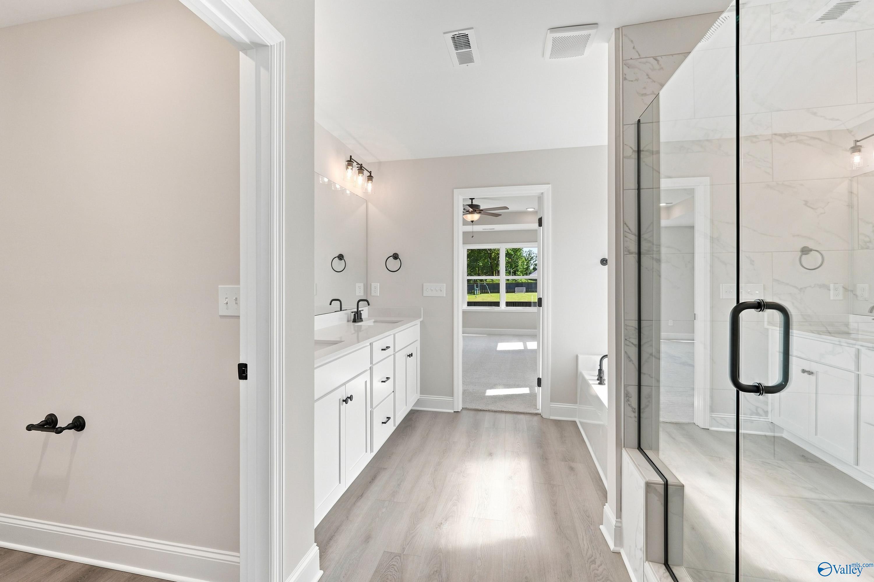 Modern primary bathroom with dual vanity, glass walk-in shower, and soaking tub in Davidson Homes Chelsea B, New Market, AL