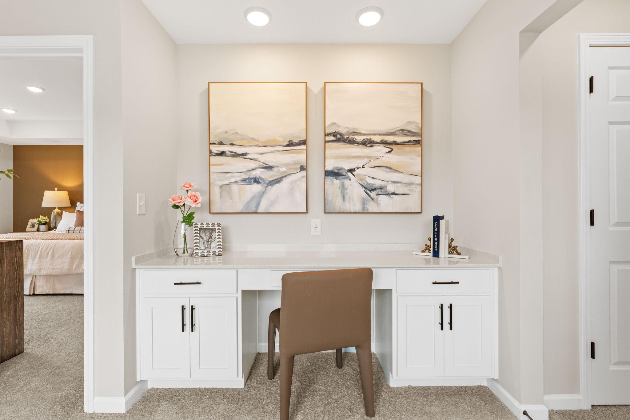 Cozy home office in Hemingway Cumming GA with white desk, brown chair, abstract art, and pink roses
