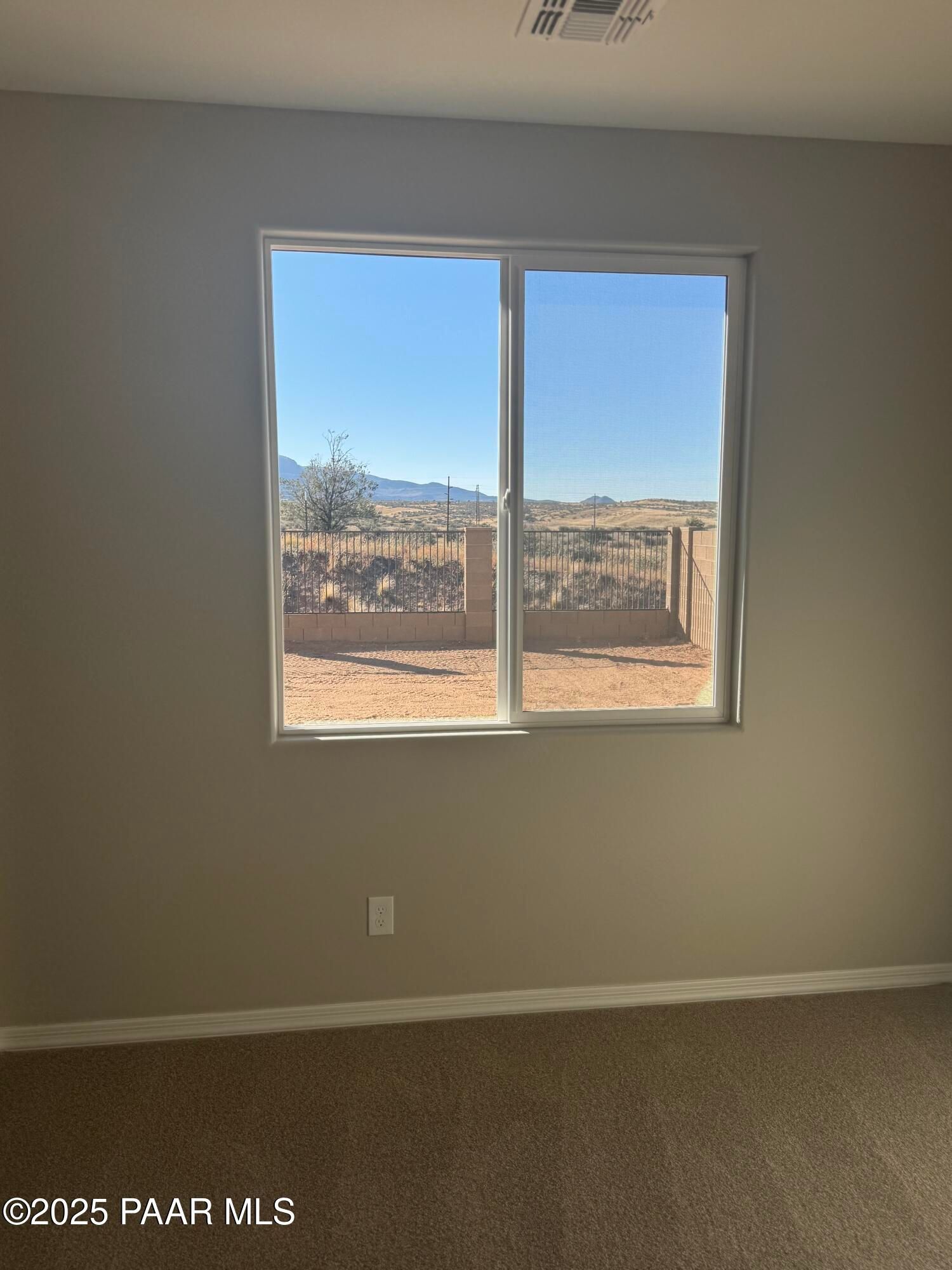 Bright bedroom with sliding glass door overlooking Prescott Arizona desert mountains and fenced yard in The Monarch E home