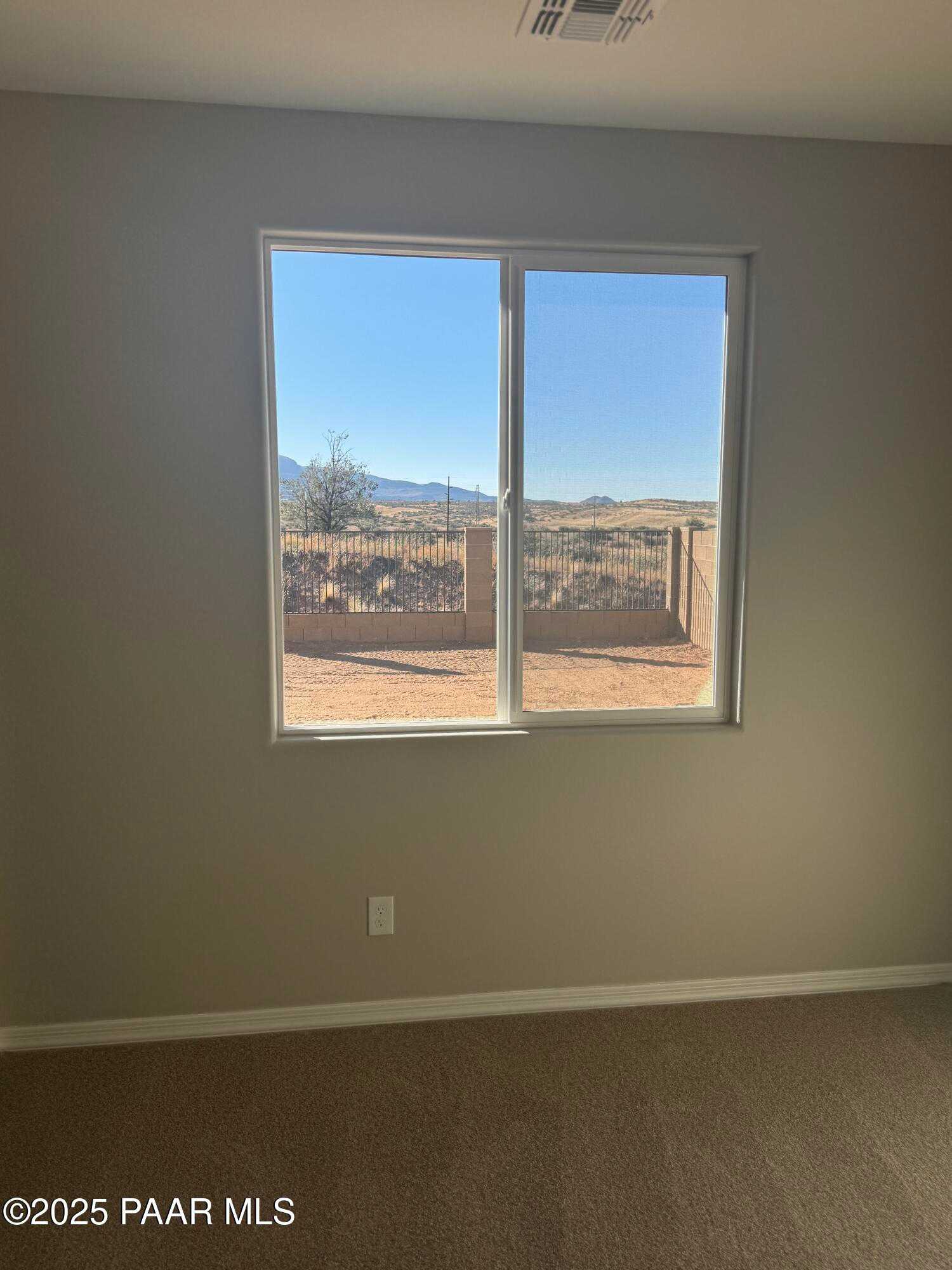 Bright bedroom with sliding glass door overlooking Prescott Arizona desert mountains and fenced yard in The Monarch E home