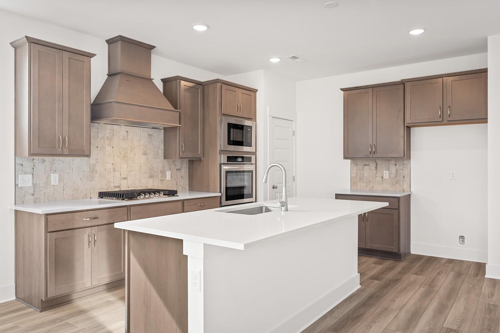 Modern kitchen with white quartz island, shaker cabinets, gas range, double ovens in The Ash C floor plan, Mt. Juliet, TN