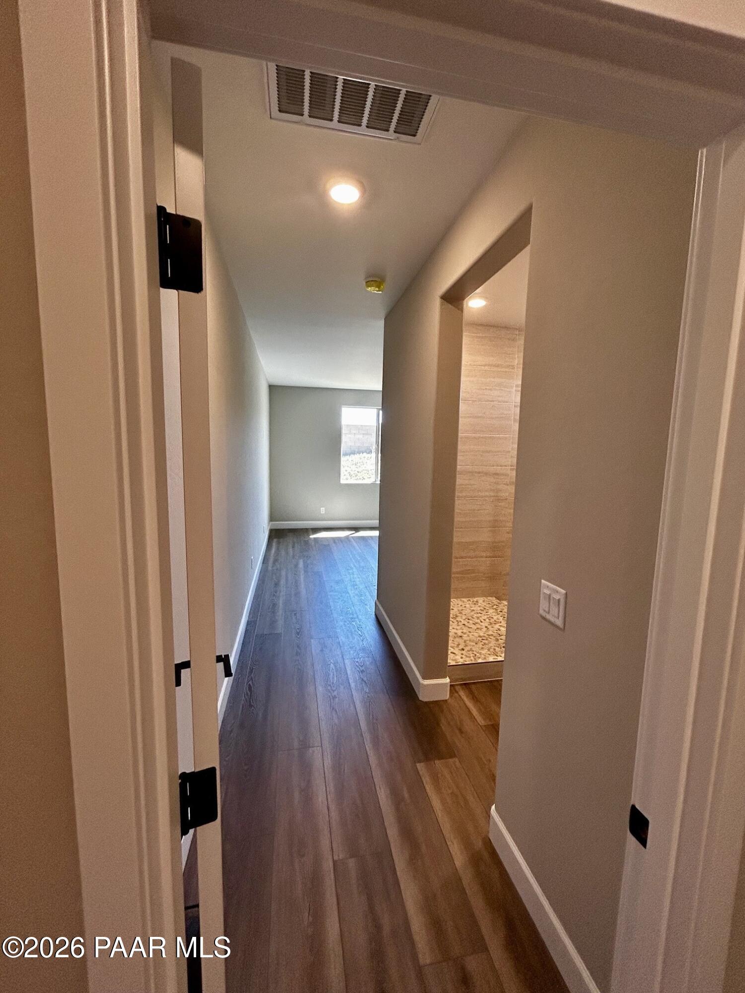 Hallway with luxury vinyl plank flooring leading to a tiled walk-in shower in The Harmony C at North Ridge, Prescott Valley