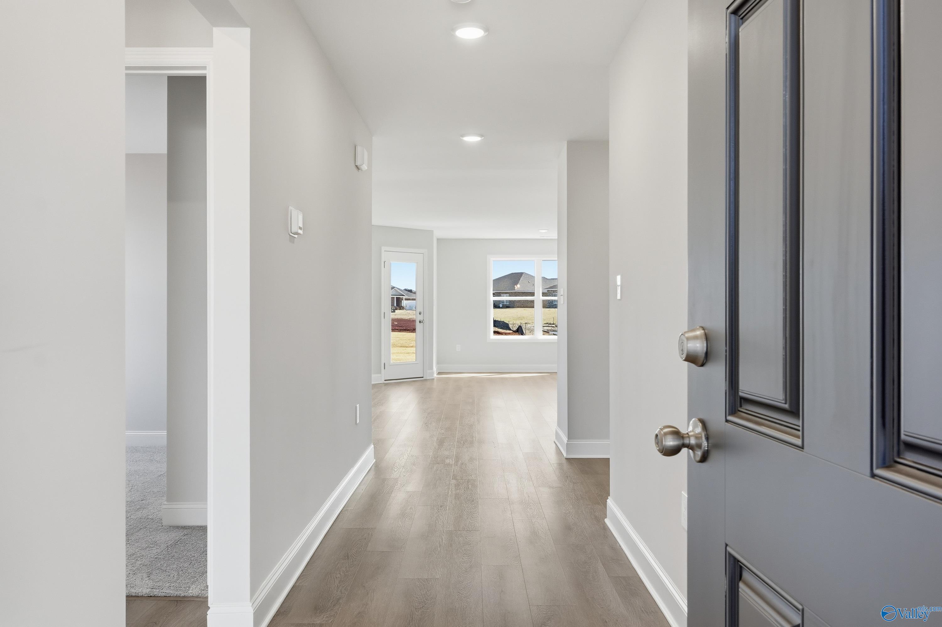 Bright hallway with hardwood floors, neutral walls, and large windows in Davidson Homes The Franklin, New Market, Alabama