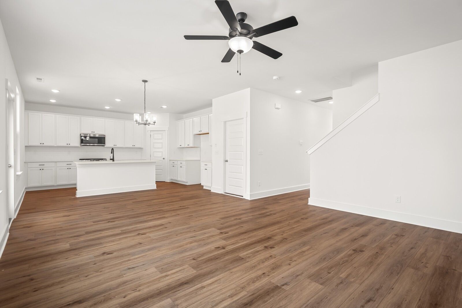 Bright open-concept kitchen with white shaker cabinets, large island, ceiling fan, and hardwood floors in Davidson Homes The Logan C, Gallatin TN