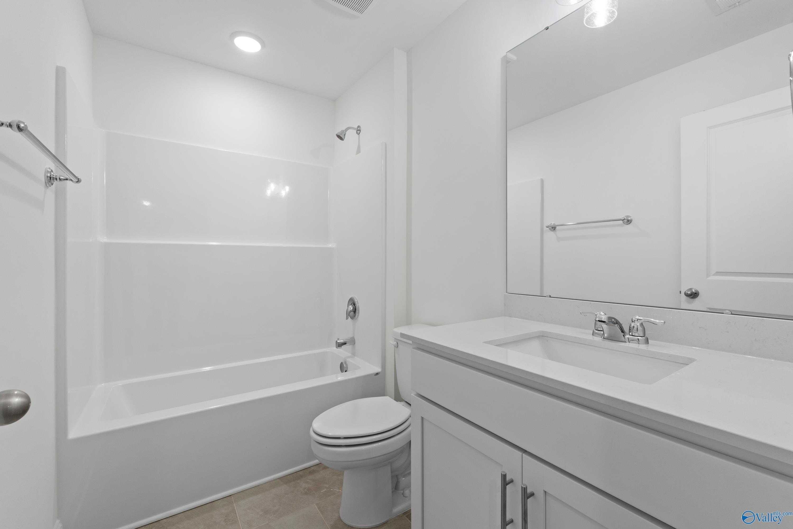 Modern white guest bathroom with bathtub shower combo, vanity sink, toilet in Davidson Homes The Rockford B with Bonus, Toney AL