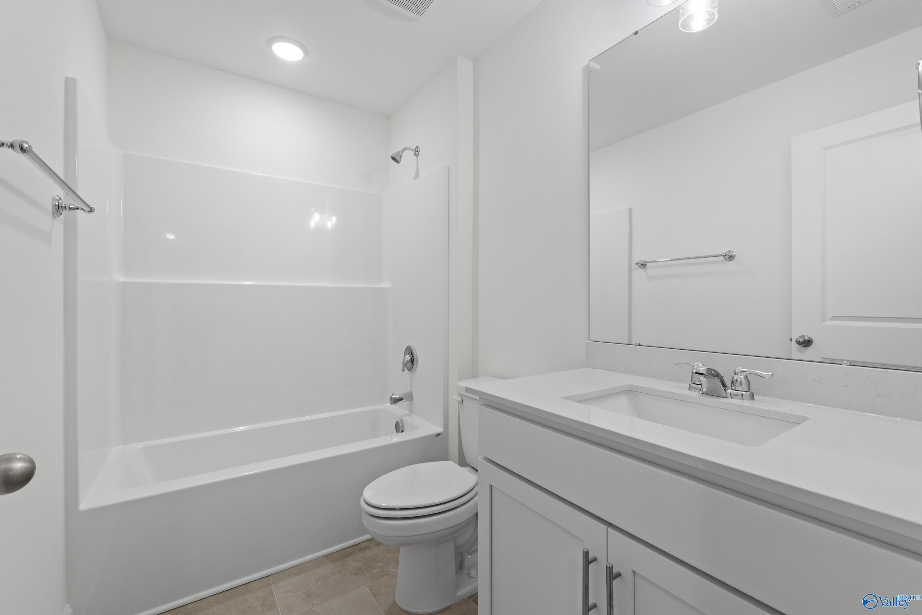 Modern white guest bathroom with bathtub shower combo, vanity sink, toilet in Davidson Homes The Rockford B with Bonus, Toney AL