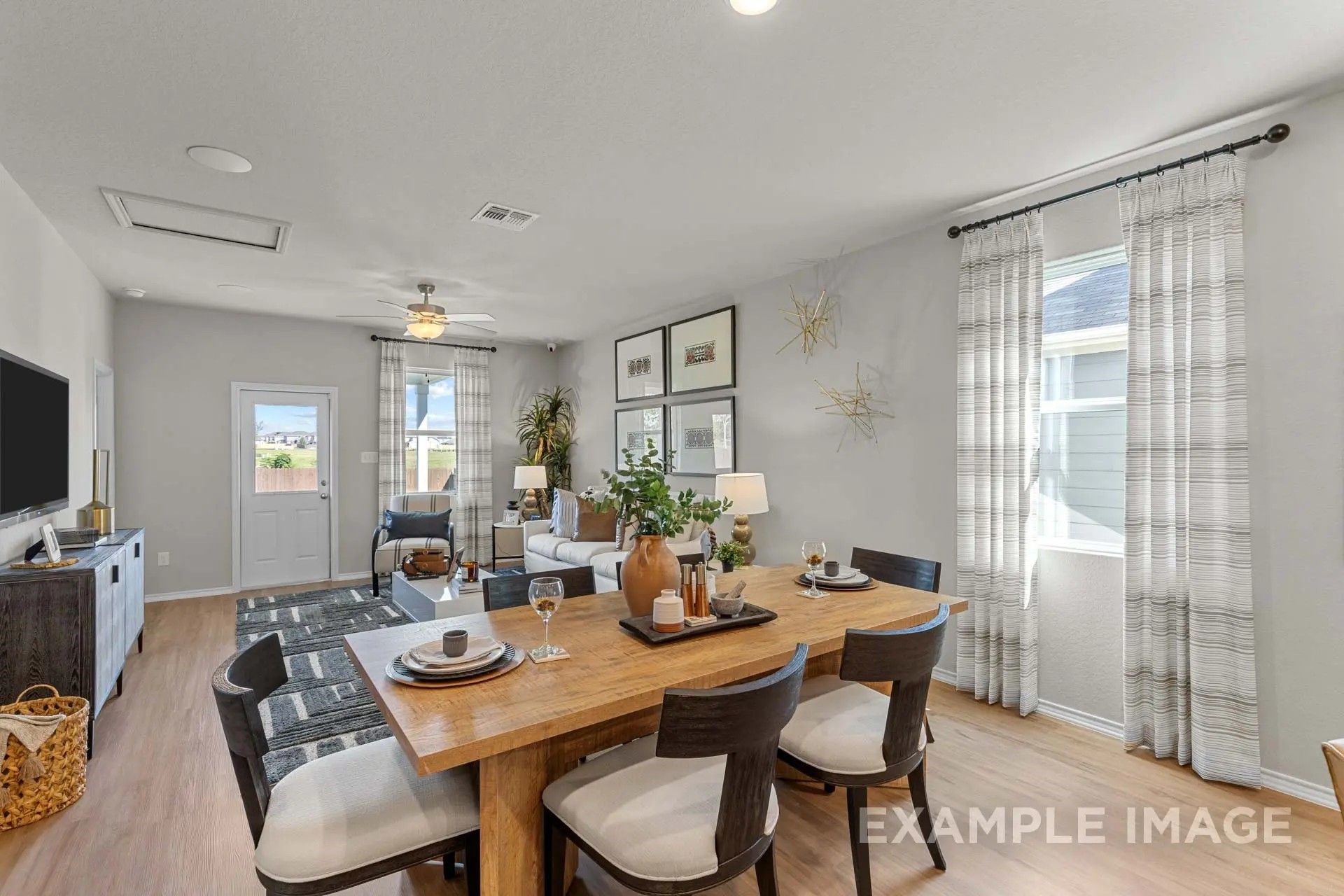 Open-concept dining and living area in The Sabine H floor plan at Heartland, Texas, featuring modern decor and wood floors.