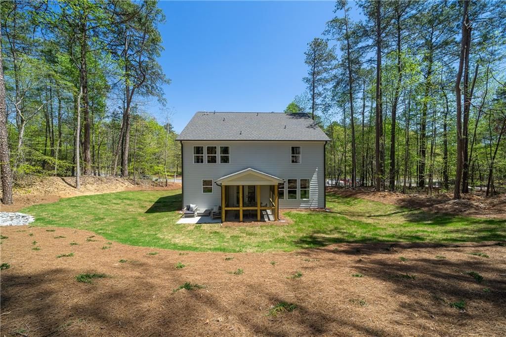 Two-story Willow B home rear exterior with screened porch, lush green yard, and pine trees in Riverwood, Dallas, Georgia