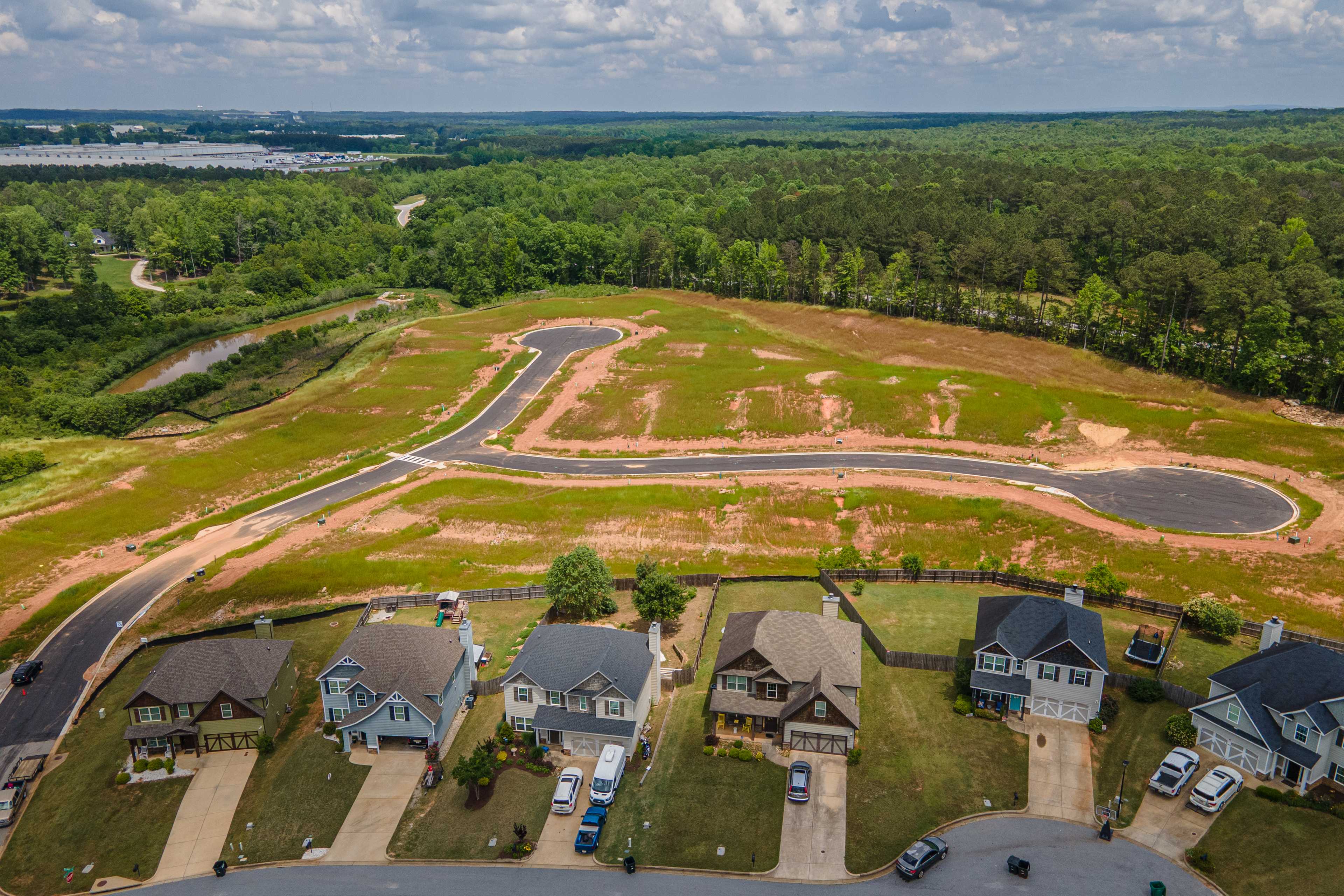 Aerial view of Anderson Lakes neighborhood in Opelika Alabama with new Davidson Homes, curved roads, forested surroundings, and distant lake