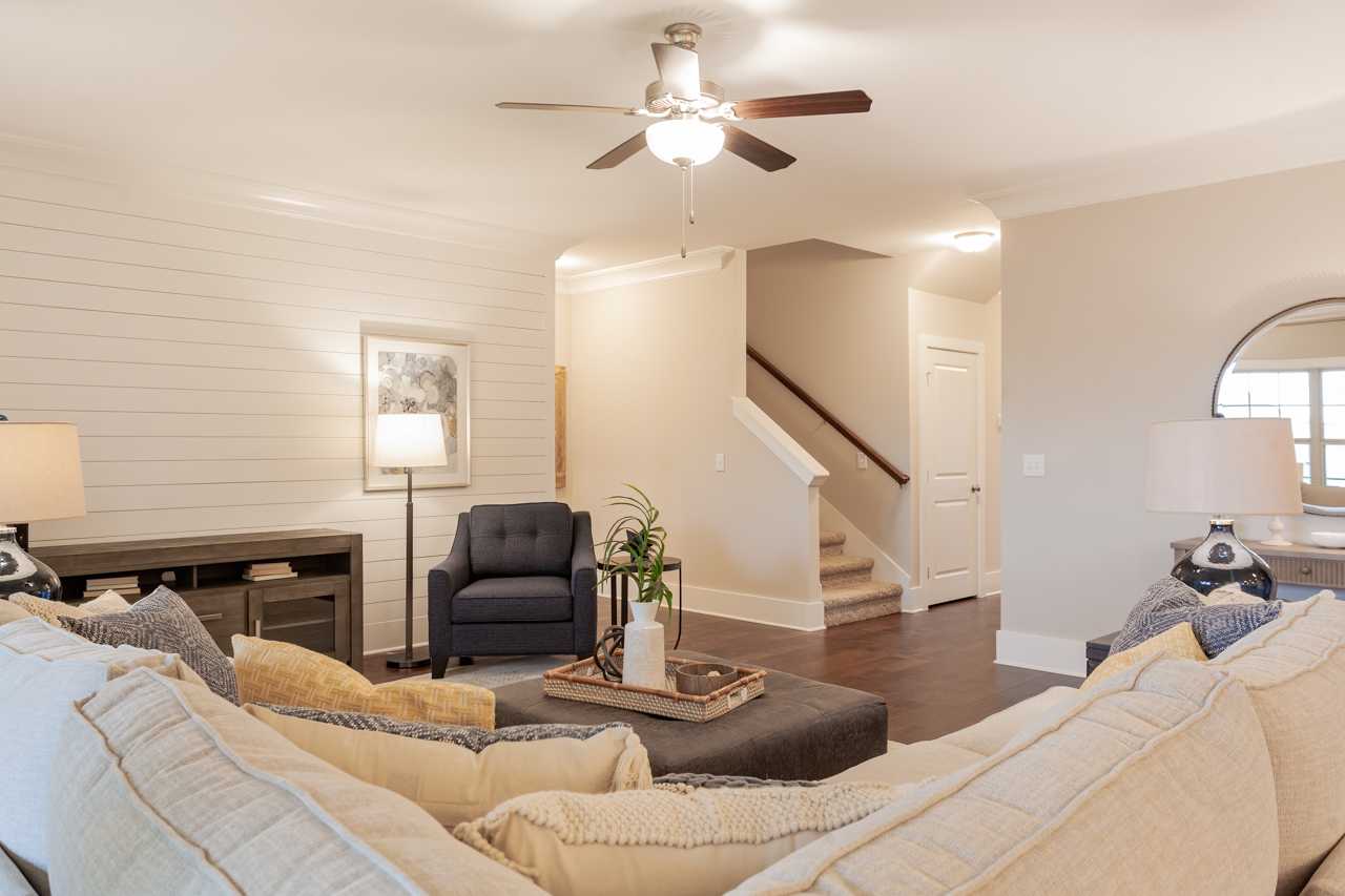 Open-concept living room in Laurenwood Preserve, Madison AL with shiplap walls, hardwood floors, ceiling fan, and modern gray sectional sofa