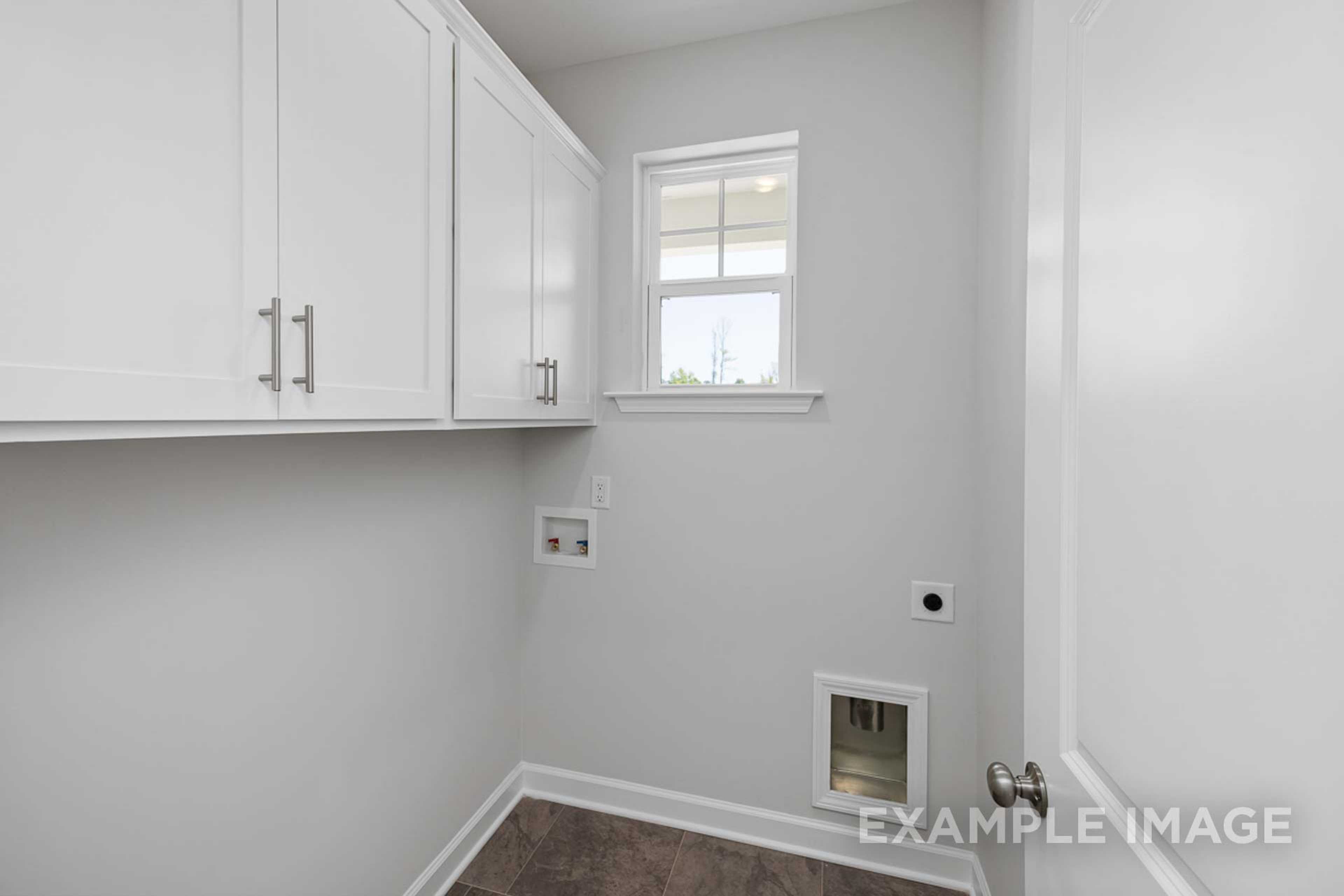Spacious laundry room in The Carter A by Davidson Homes featuring white cabinets, gray walls, window, outlets, and pet door