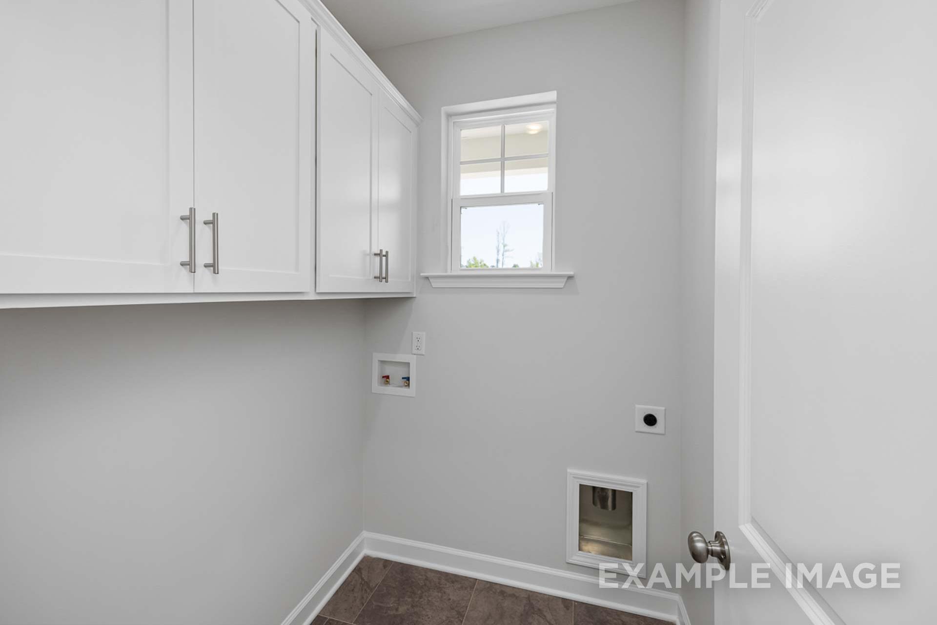 Laundry room in The Carter C with white shaker cabinets, gray walls, window, outlets, and pet door