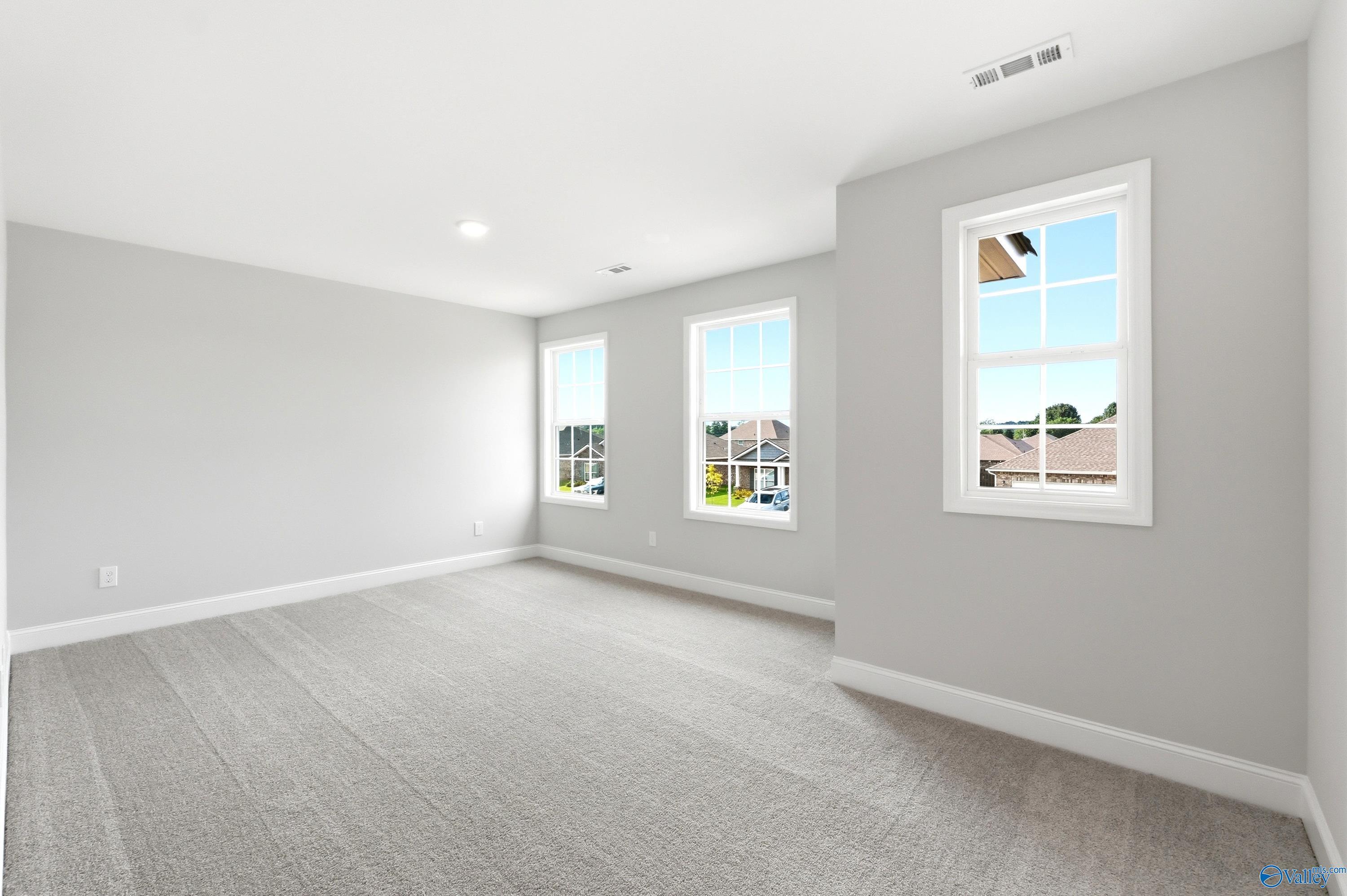 Bright, spacious bedroom with neutral walls and carpet in The Shelby A floor plan at Clearview in Hazel Green, Alabama.