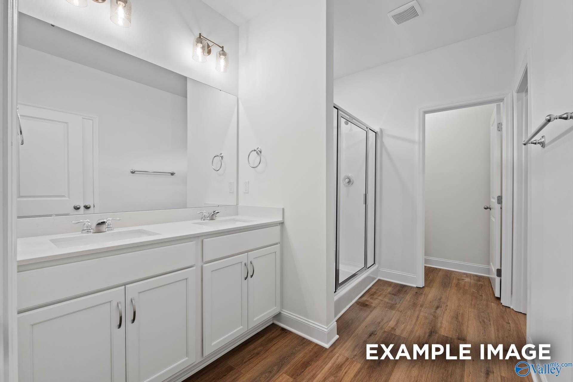 Modern master bathroom featuring double vanity, white shaker cabinets, and frameless walk-in shower in Davidson Homes The Daphne D, Athens, Alabama