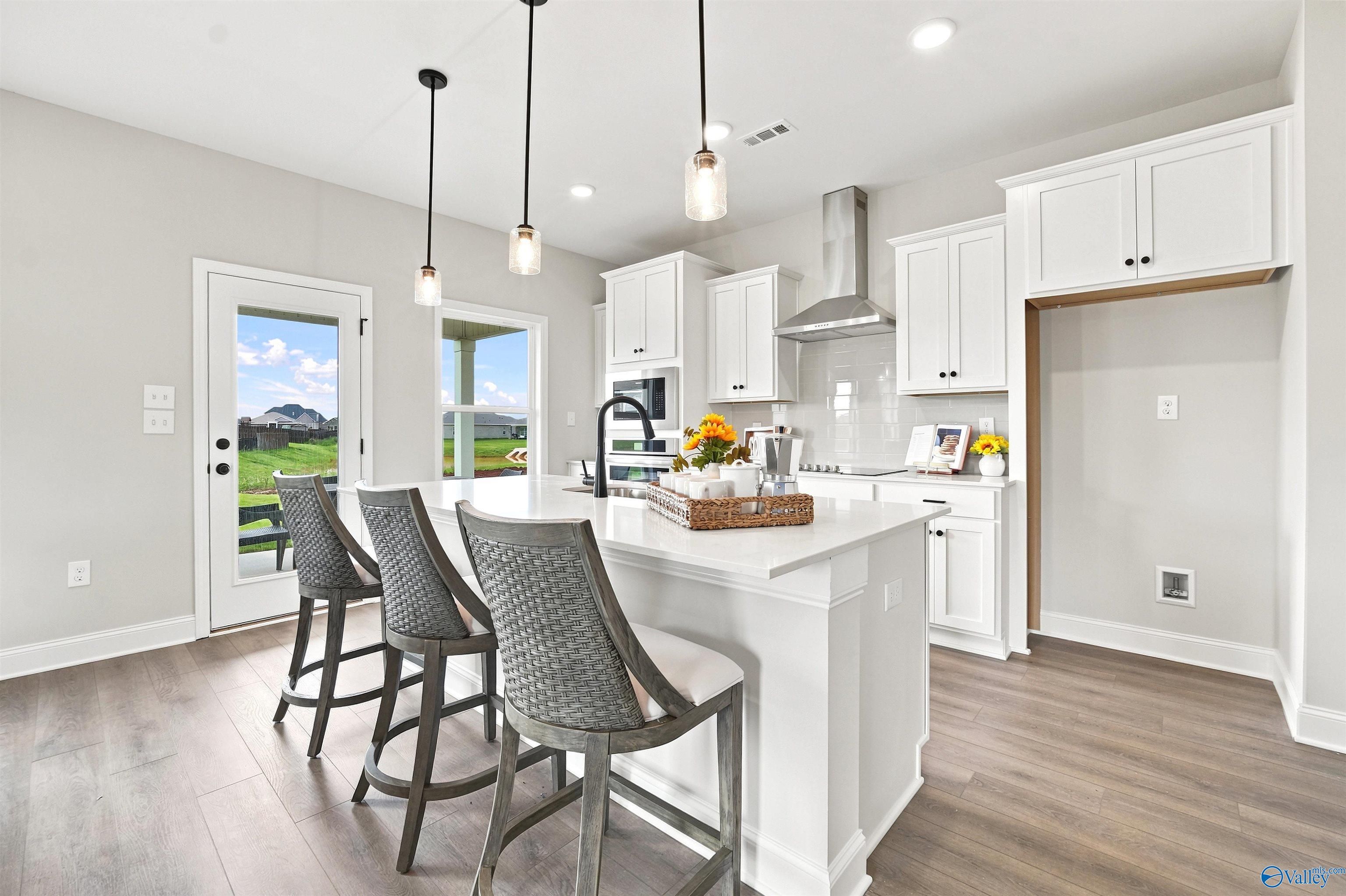 Modern kitchen with white cabinets and quartz island in The Burton B floor plan at Heritage Lakes, New Market, Alabama.