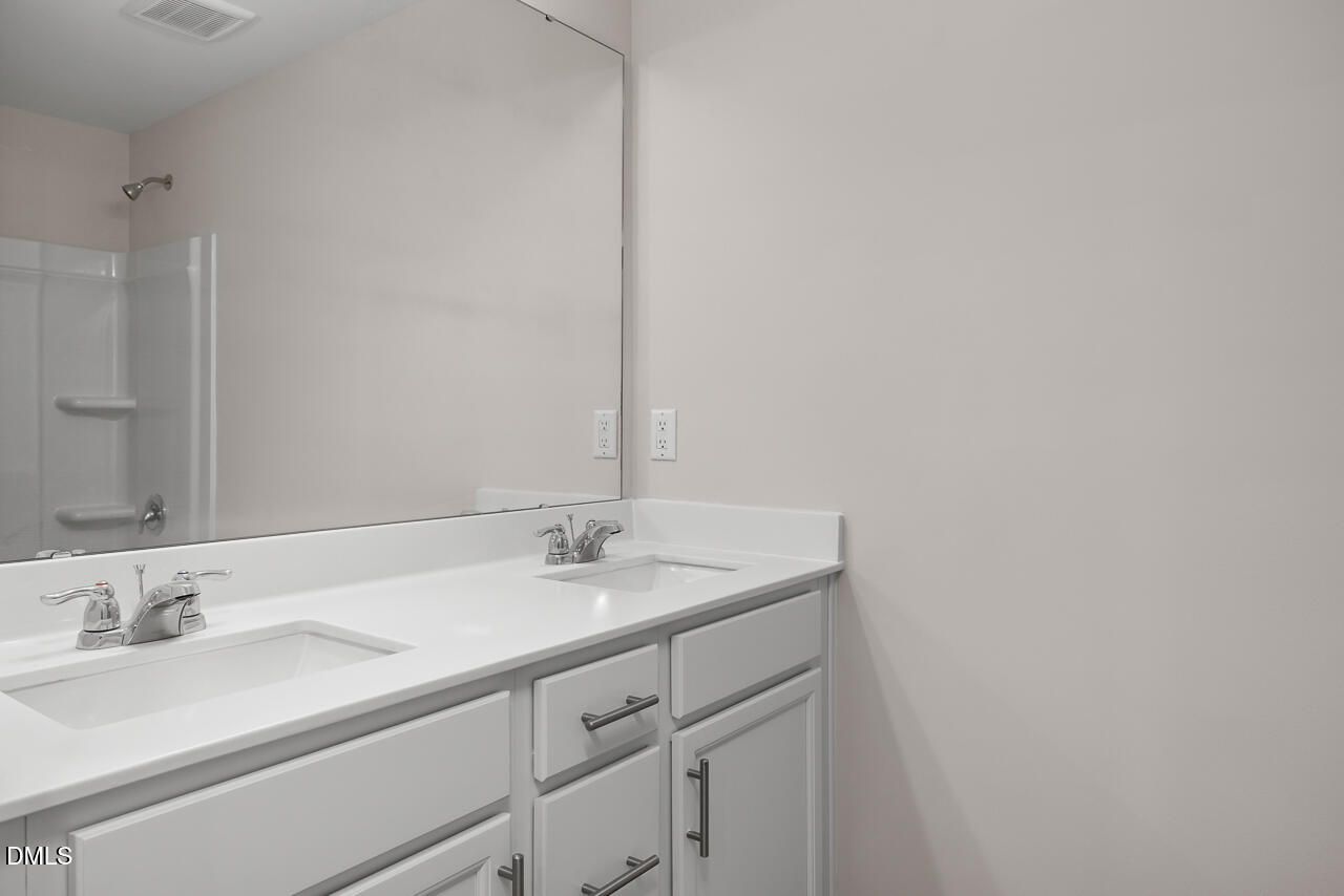 Modern master bathroom featuring double white vanity, quartz countertop, large mirror, and walk-in glass shower in Davidson Homes The Grace C, Lillington, NC