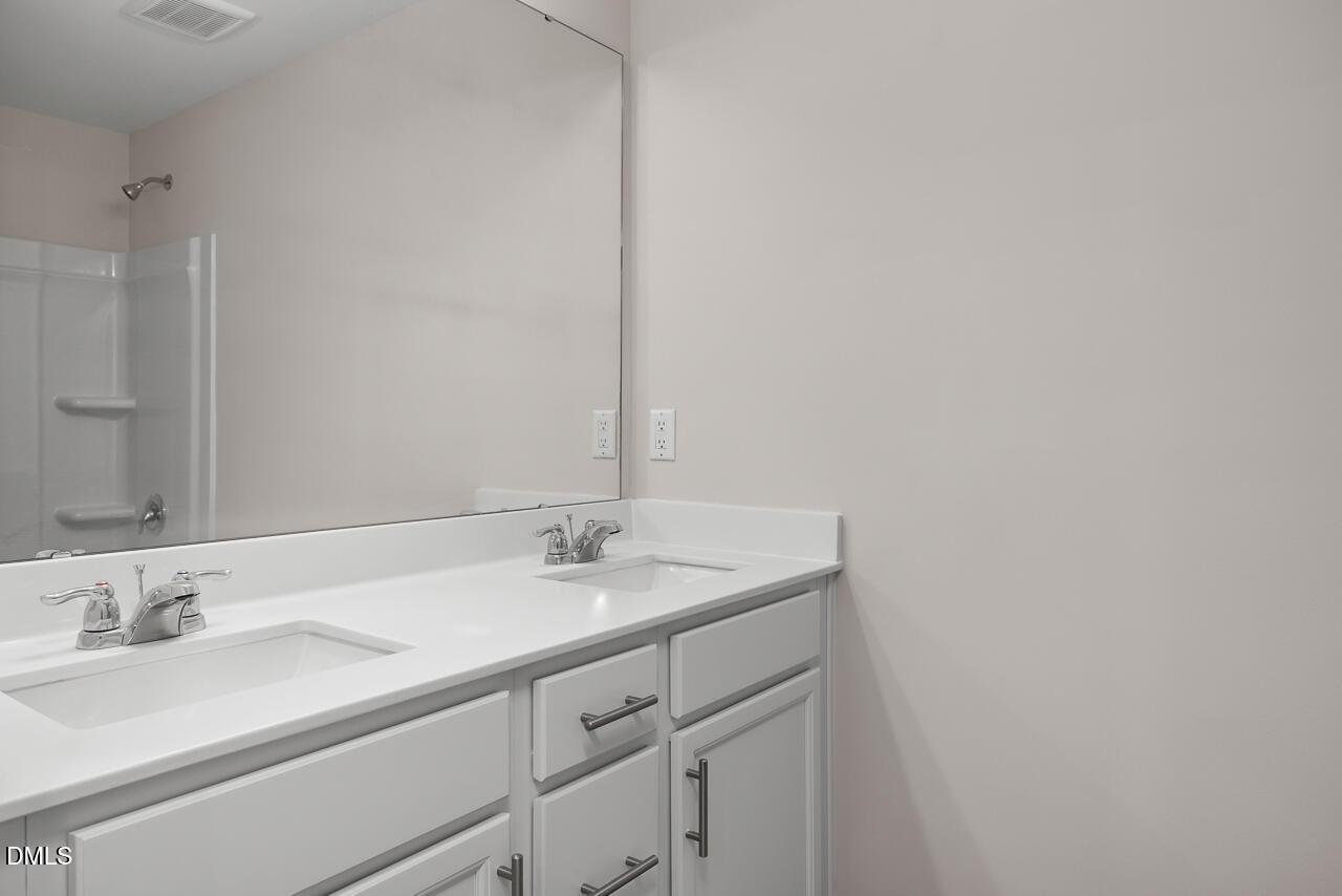 Modern master bathroom featuring double white vanity, quartz countertop, large mirror, and walk-in glass shower in Davidson Homes The Grace C, Lillington, NC