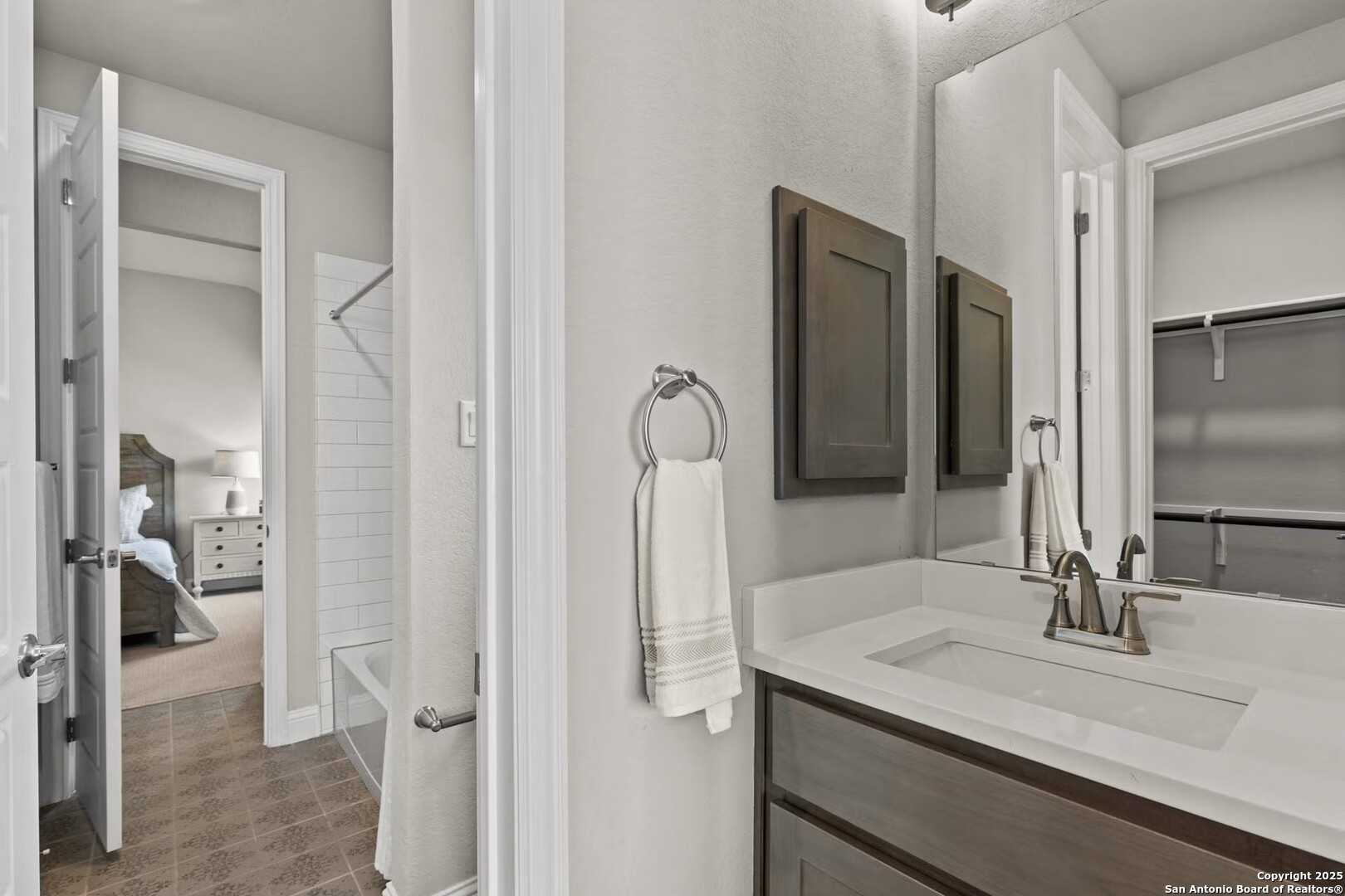 Spacious master bathroom with soaking tub, modern vanity, and adjacent bedroom in Davidson Homes The Garner A, Castroville, Texas