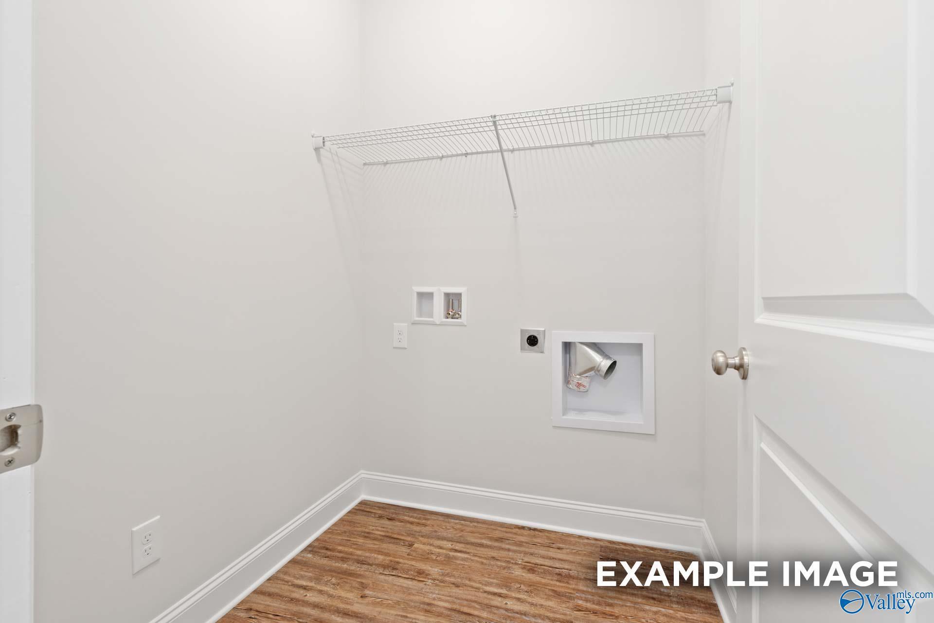 Bright laundry closet with wire shelving, washer-dryer hookups, and hardwood floors in Davidson Homes The Asheville C, Meridianville, Alabama