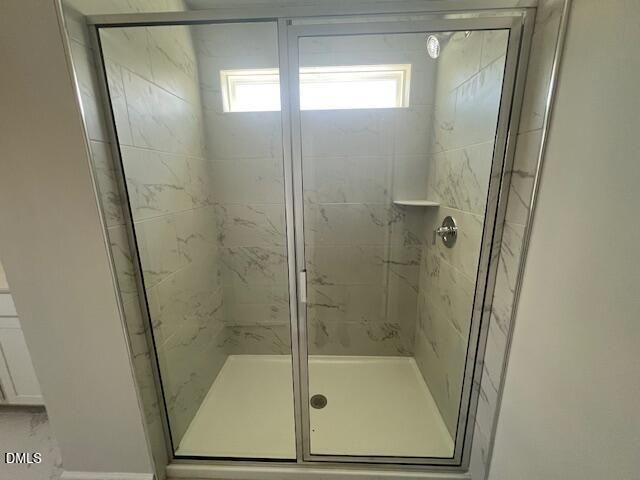 Modern frameless glass shower with marble-veined tiles and niche shelf in Davidson Homes The Adalynn A, Lillington, NC