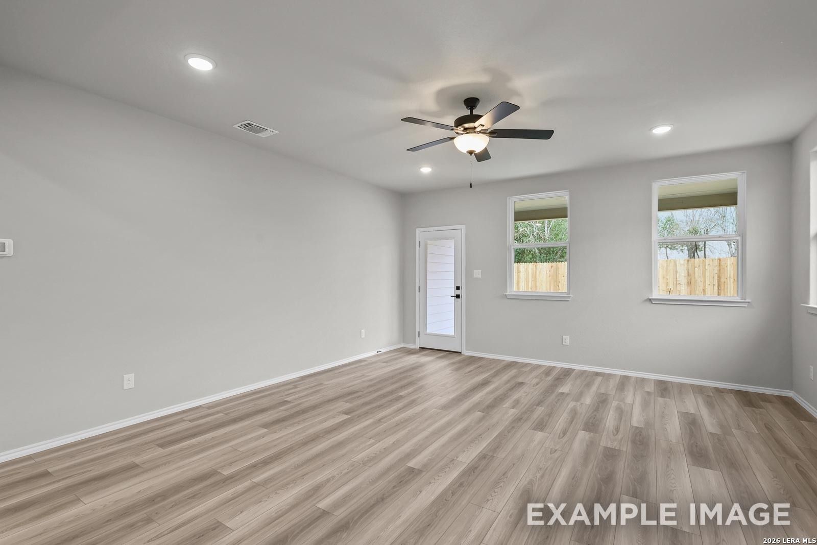 Spacious living room with wood-style flooring and ceiling fan in The Glenwood E floor plan, Royal Crest, San Antonio.