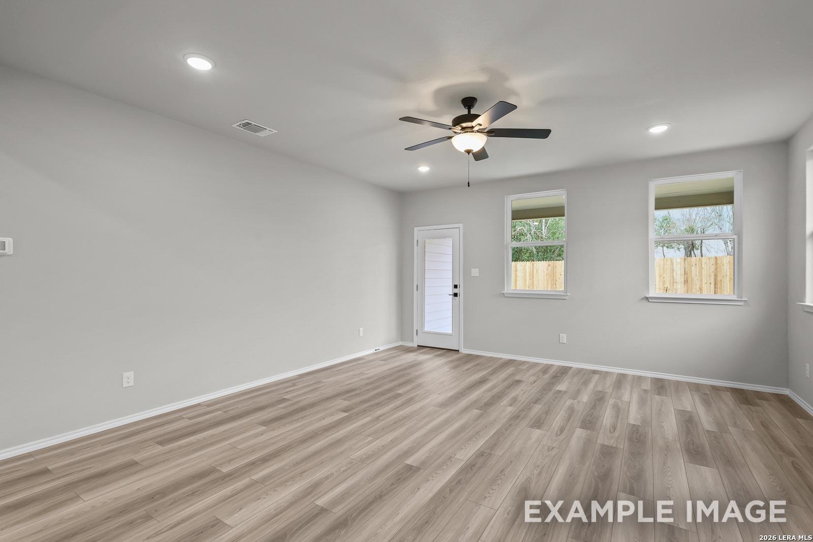 Spacious living room with wood-style flooring and ceiling fan in The Glenwood E floor plan, Royal Crest, San Antonio.
