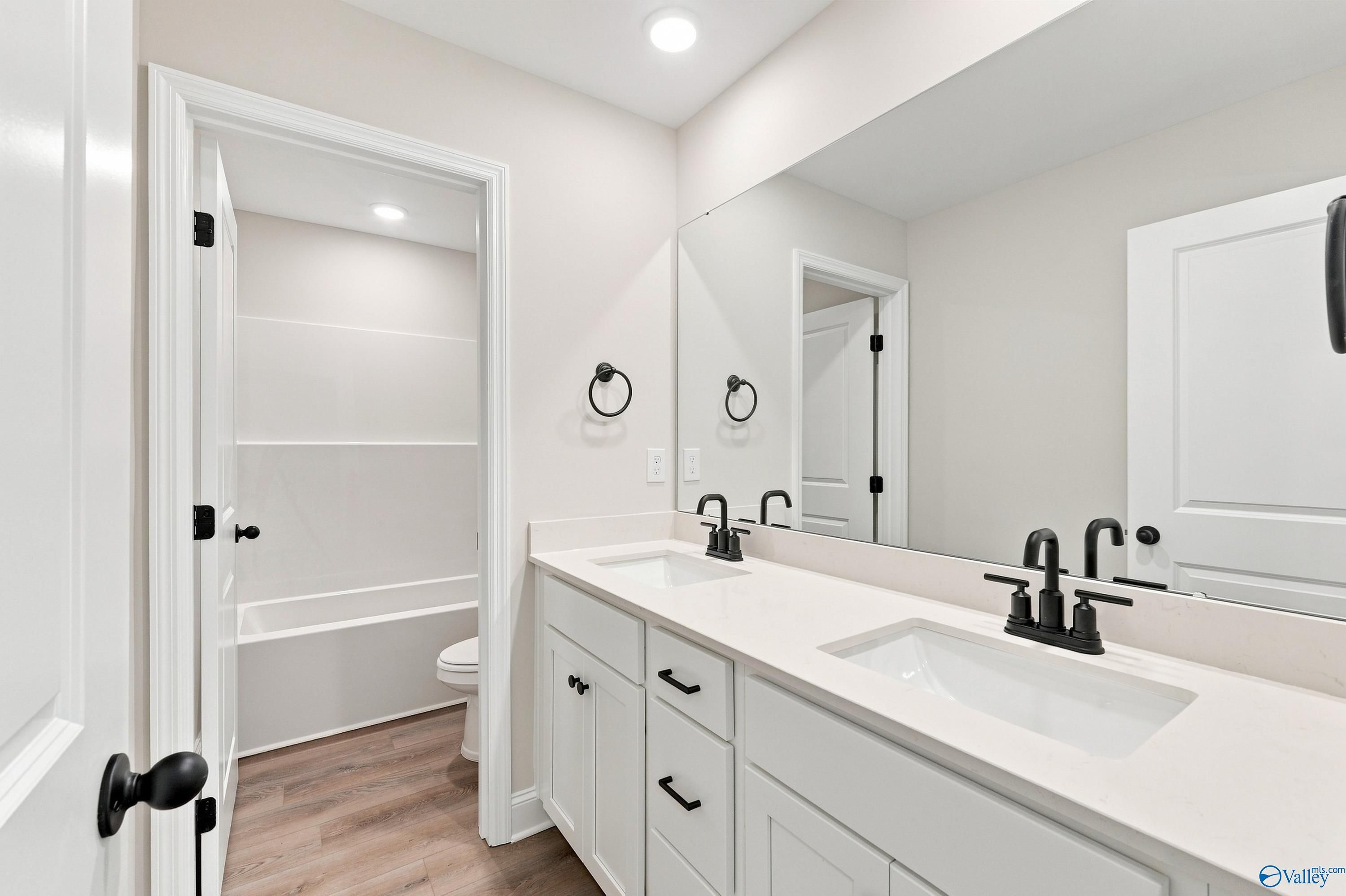 Modern white bathroom with dual vanity, matte black fixtures, and separate tub area in Davidson Homes' The Chelsea B, New Market, AL