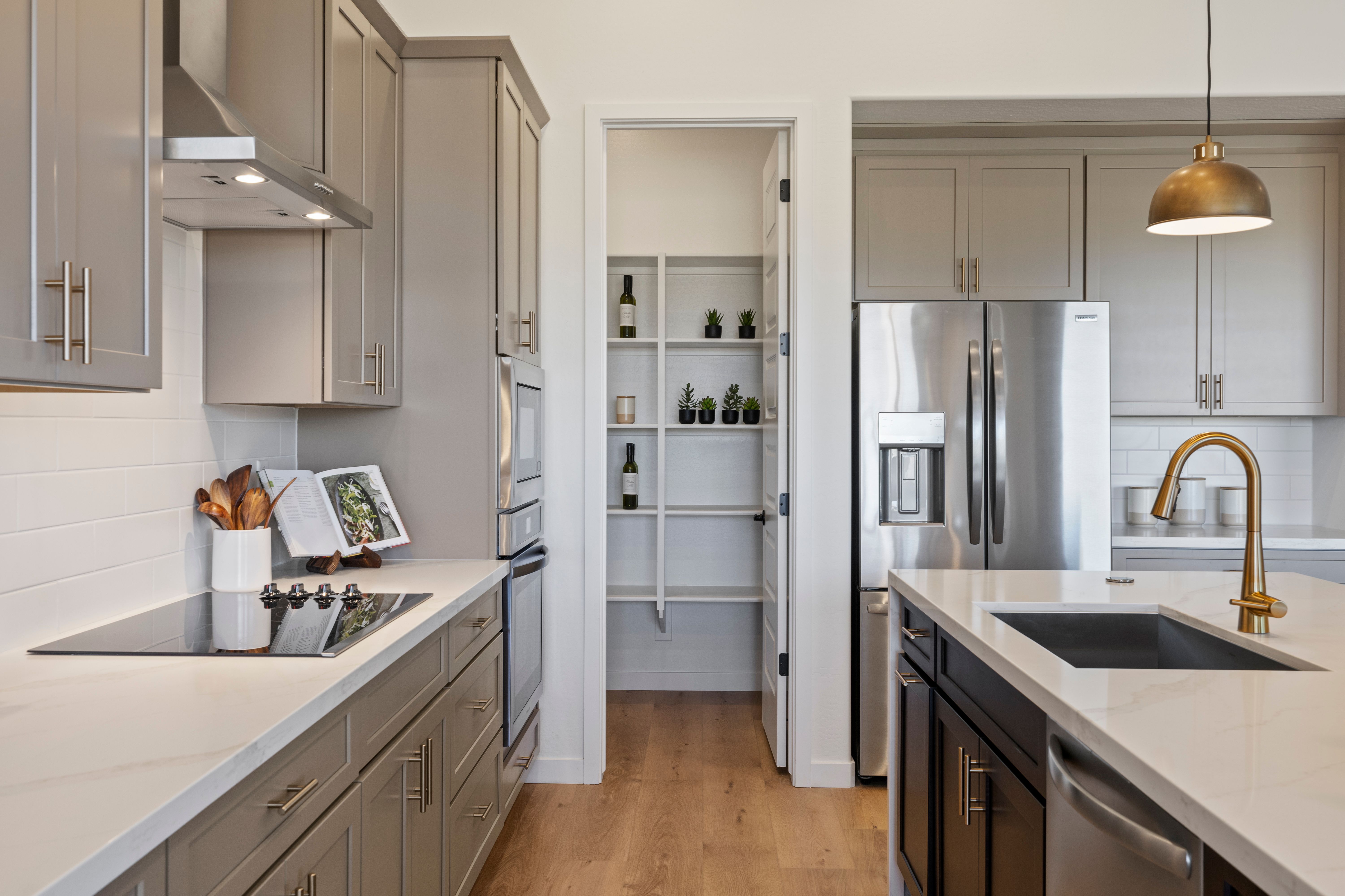 Modern kitchen in Hidden Hills Prescott AZ by Davidson Homes featuring gray shaker cabinets, white quartz island, stainless appliances, and open pantry