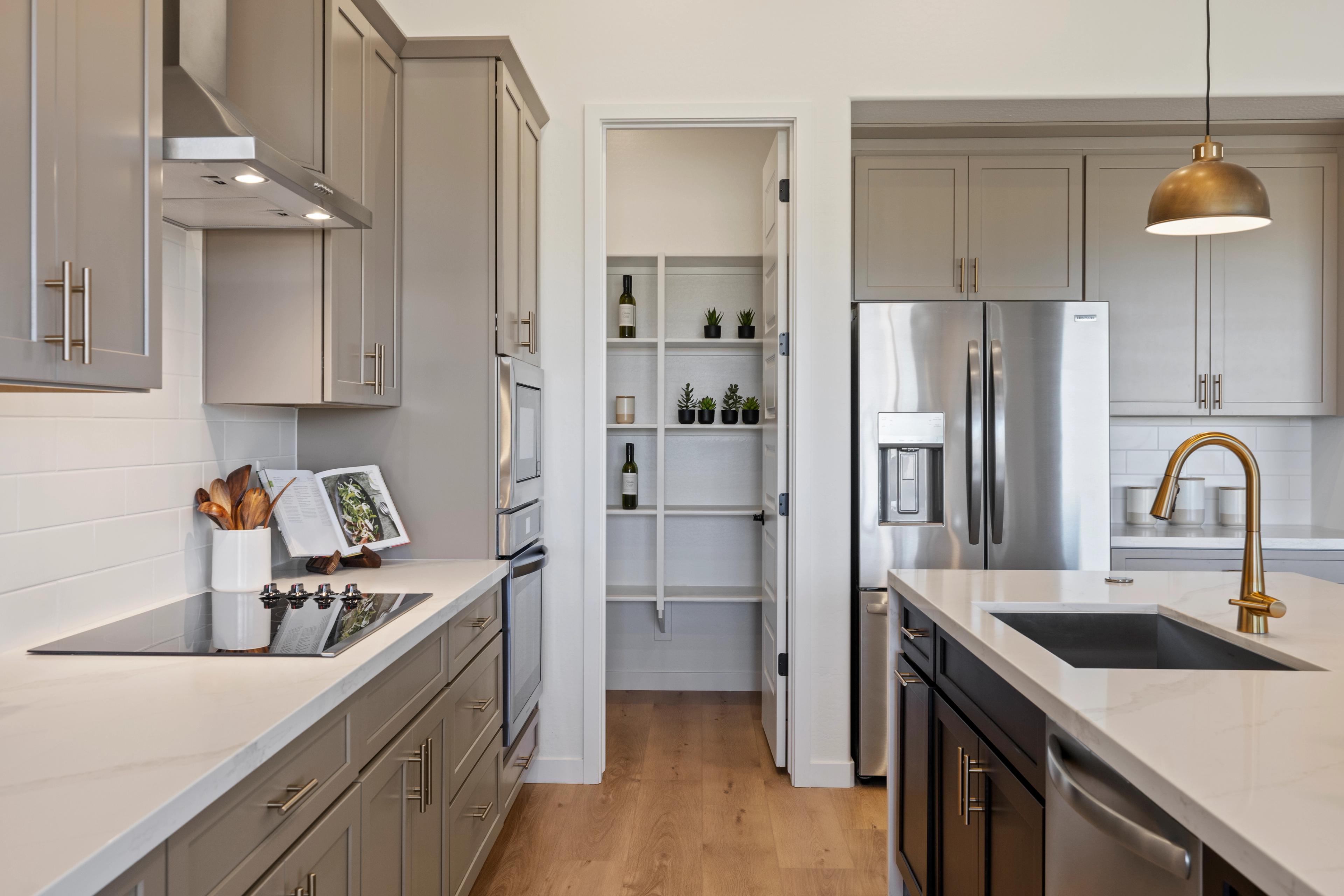 Modern kitchen in Hidden Hills Prescott AZ by Davidson Homes featuring gray shaker cabinets, white quartz island, stainless appliances, and open pantry