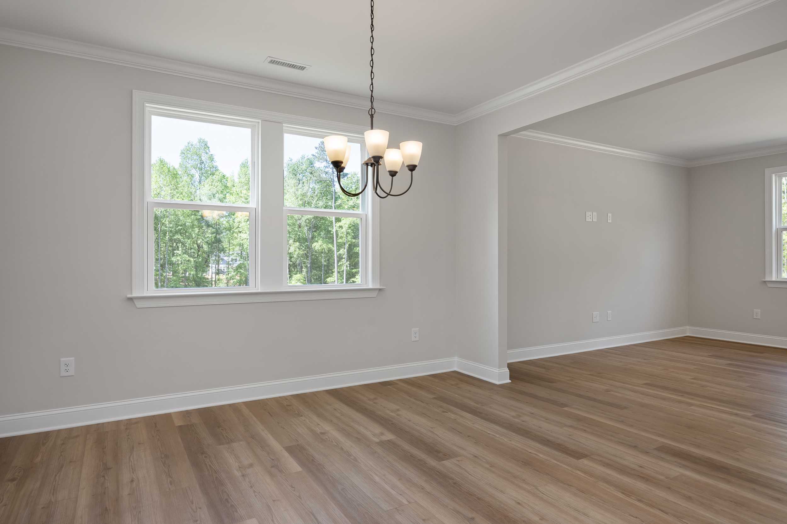 Spacious dining room in The Beech C home with hardwood floors, chandelier, gray walls, and large windows