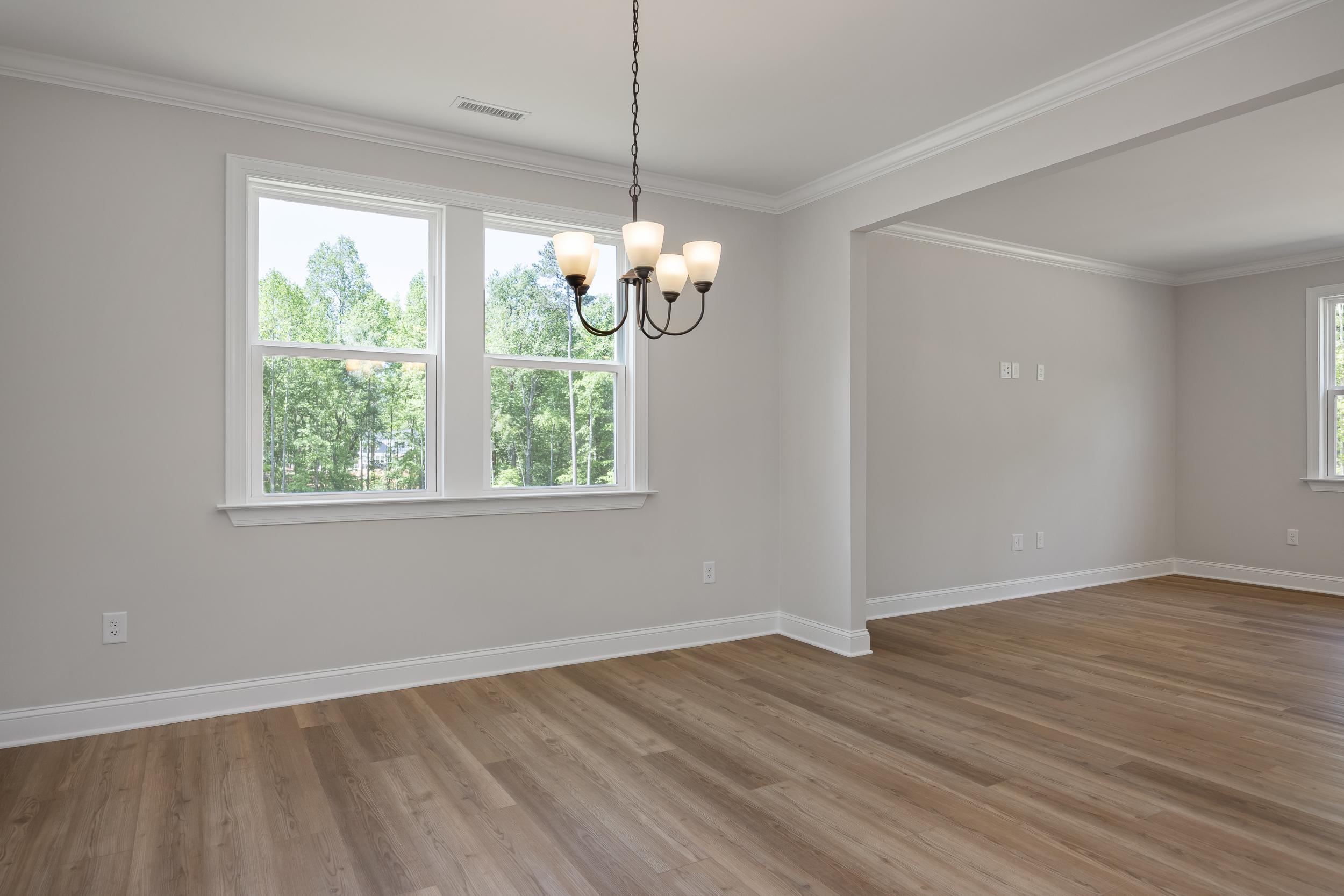 Bright dining room in The Beech A featuring hardwood floors, four-light chandelier, and large windows with tree views