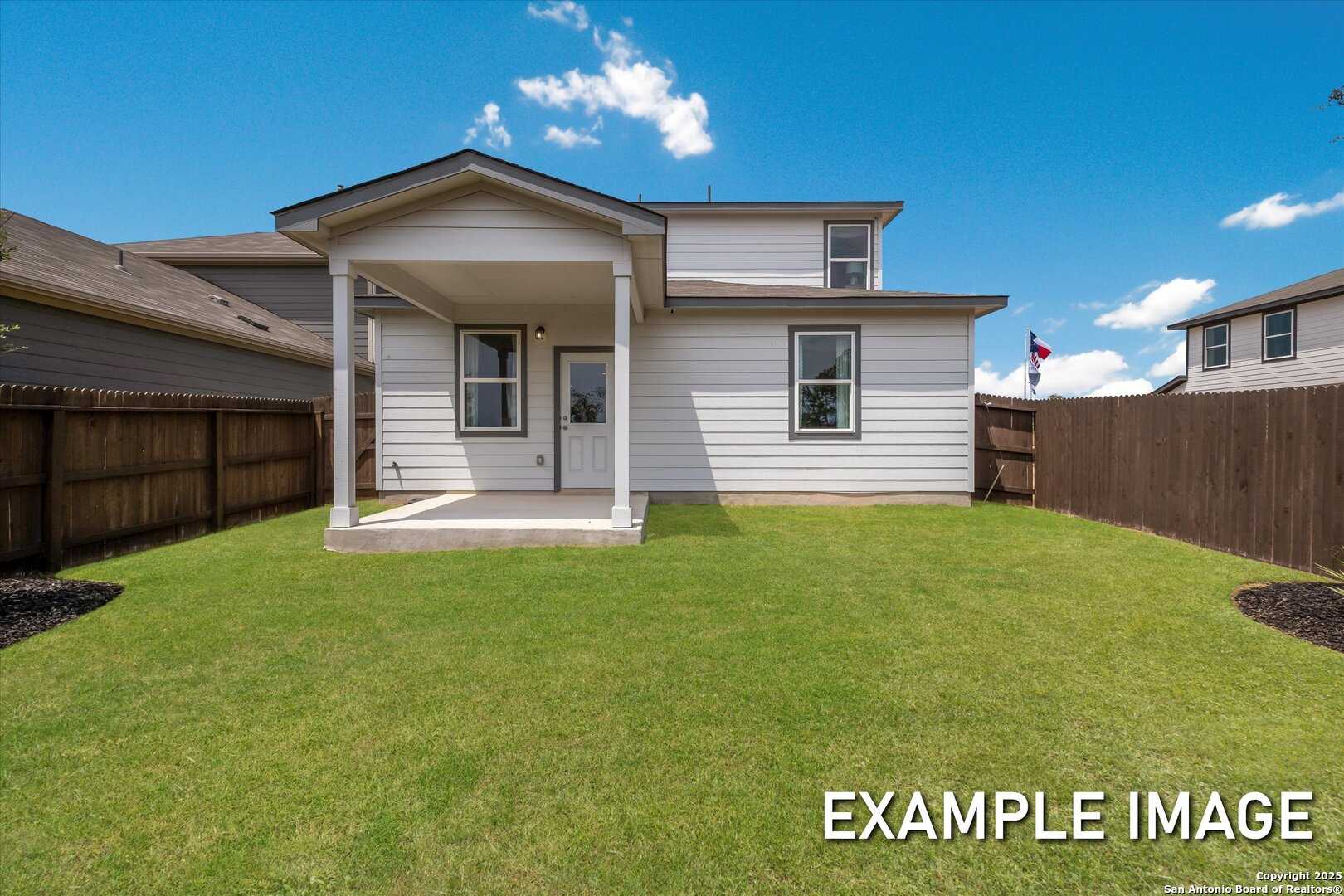 Two-story Sabine C home backyard with covered patio, lush green lawn, and privacy fence in Agave, San Antonio, Texas