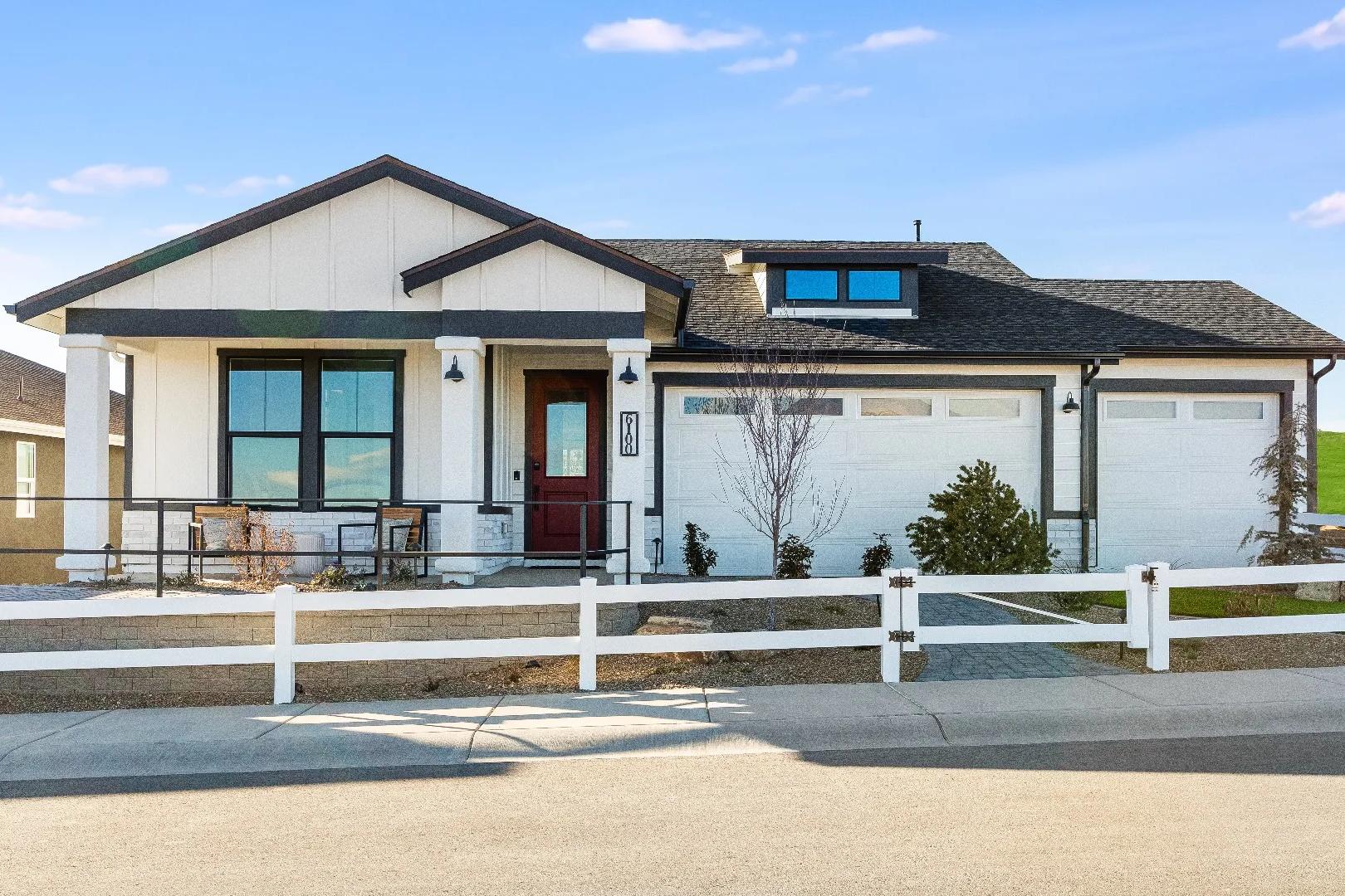 Modern farmhouse home exterior at South Ranch Western Collection in Prescott AZ with gabled roof, red door, and white fencing