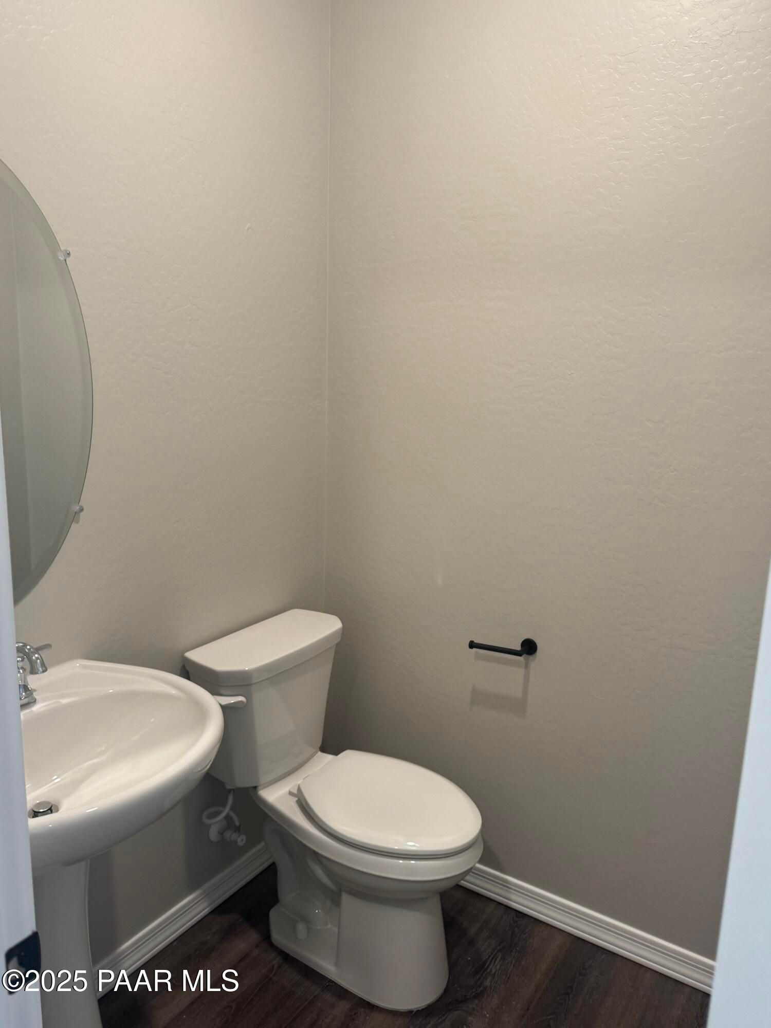 Modern half bath with white porcelain sink, toilet, and round mirror in Davidson Homes The Monarch E, Prescott, Arizona
