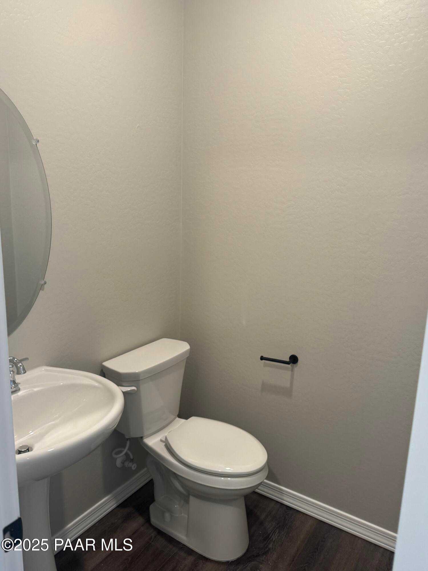 Modern half bath with white porcelain sink, toilet, and round mirror in Davidson Homes The Monarch E, Prescott, Arizona