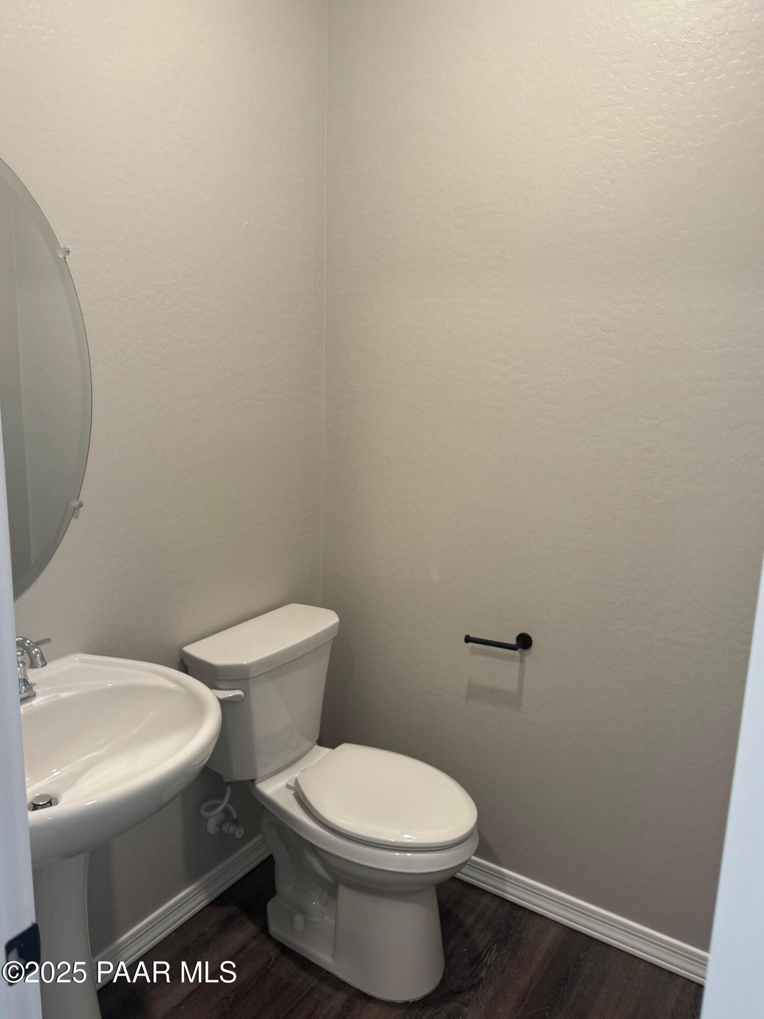 Modern half bath with white porcelain sink, toilet, and round mirror in Davidson Homes The Monarch E, Prescott, Arizona