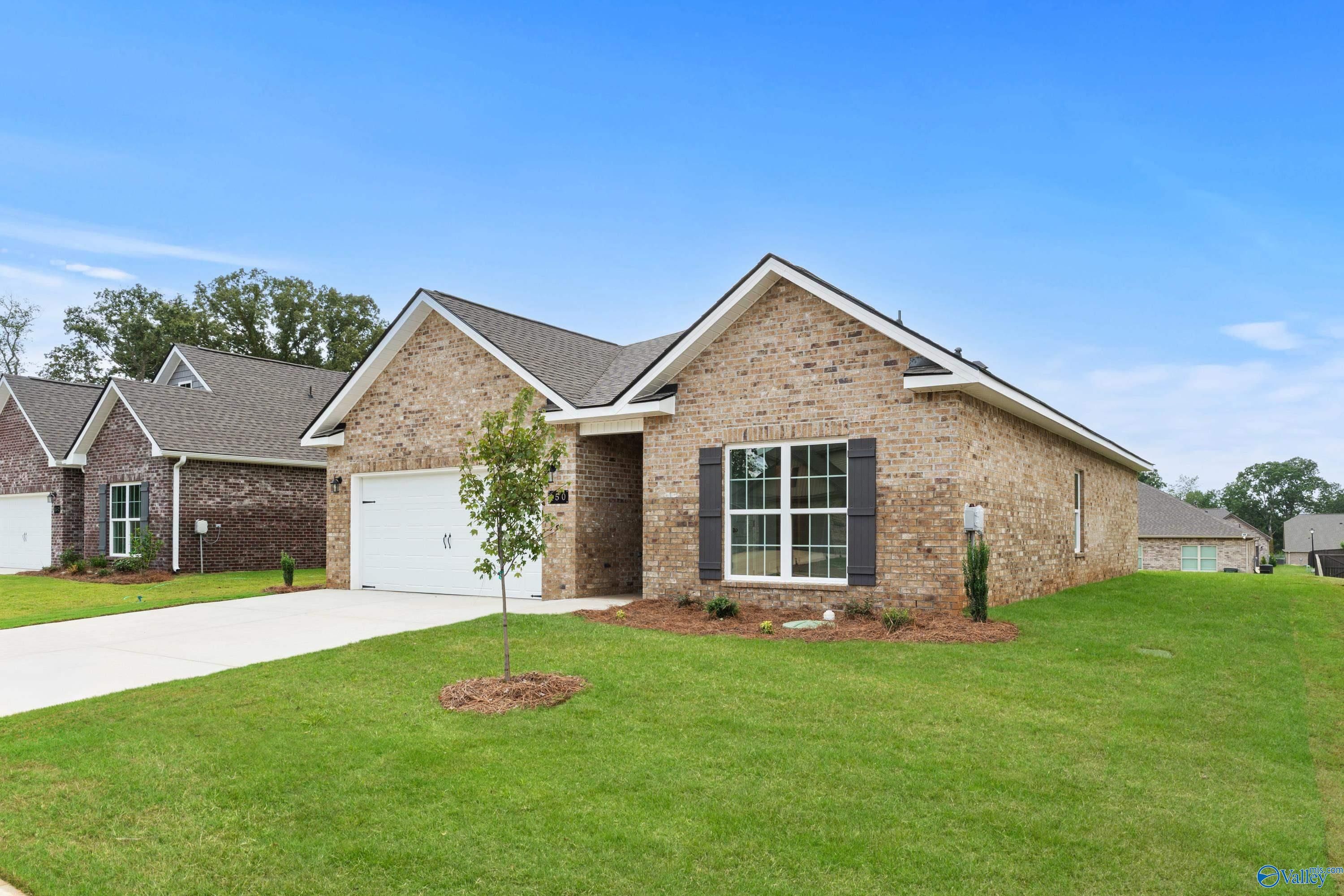 Modern single-story brick home with gabled roof, 2-car garage, large windows, and lush front yard in Creek Grove, New Market, Alabama