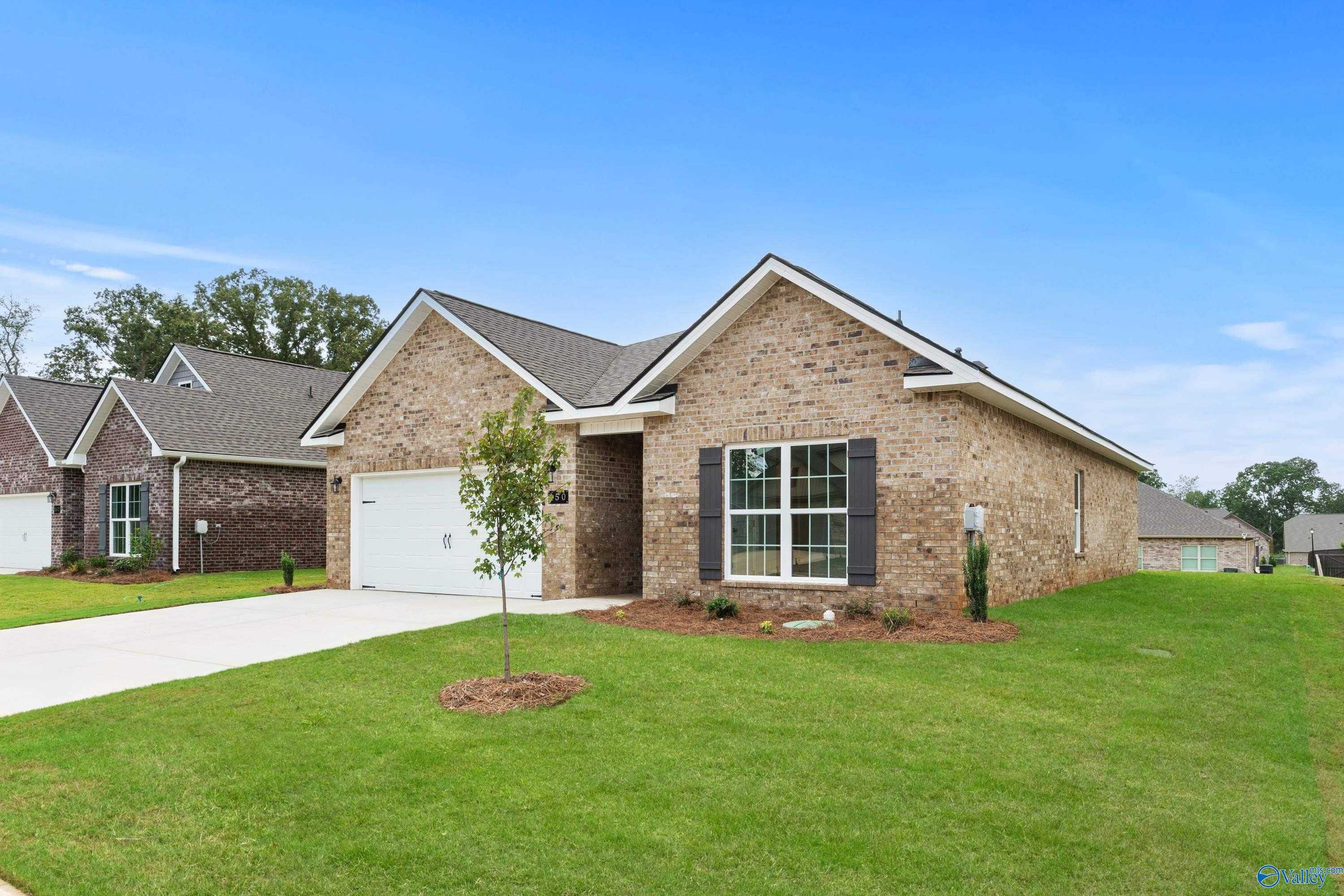 Modern single-story brick home with gabled roof, 2-car garage, large windows, and lush front yard in Creek Grove, New Market, Alabama